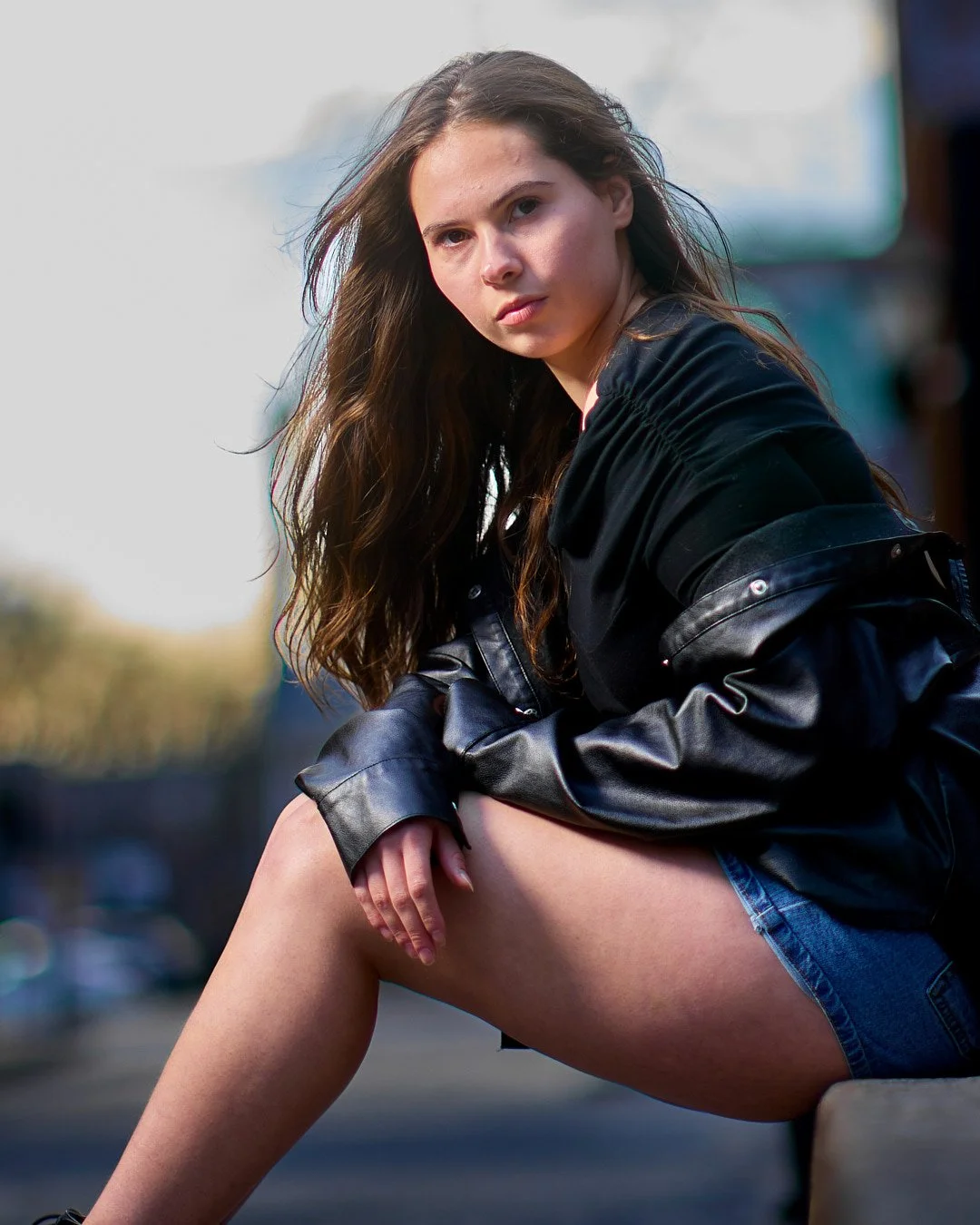 Outdoor headshot of a woman wearing a black top and leather jacket.