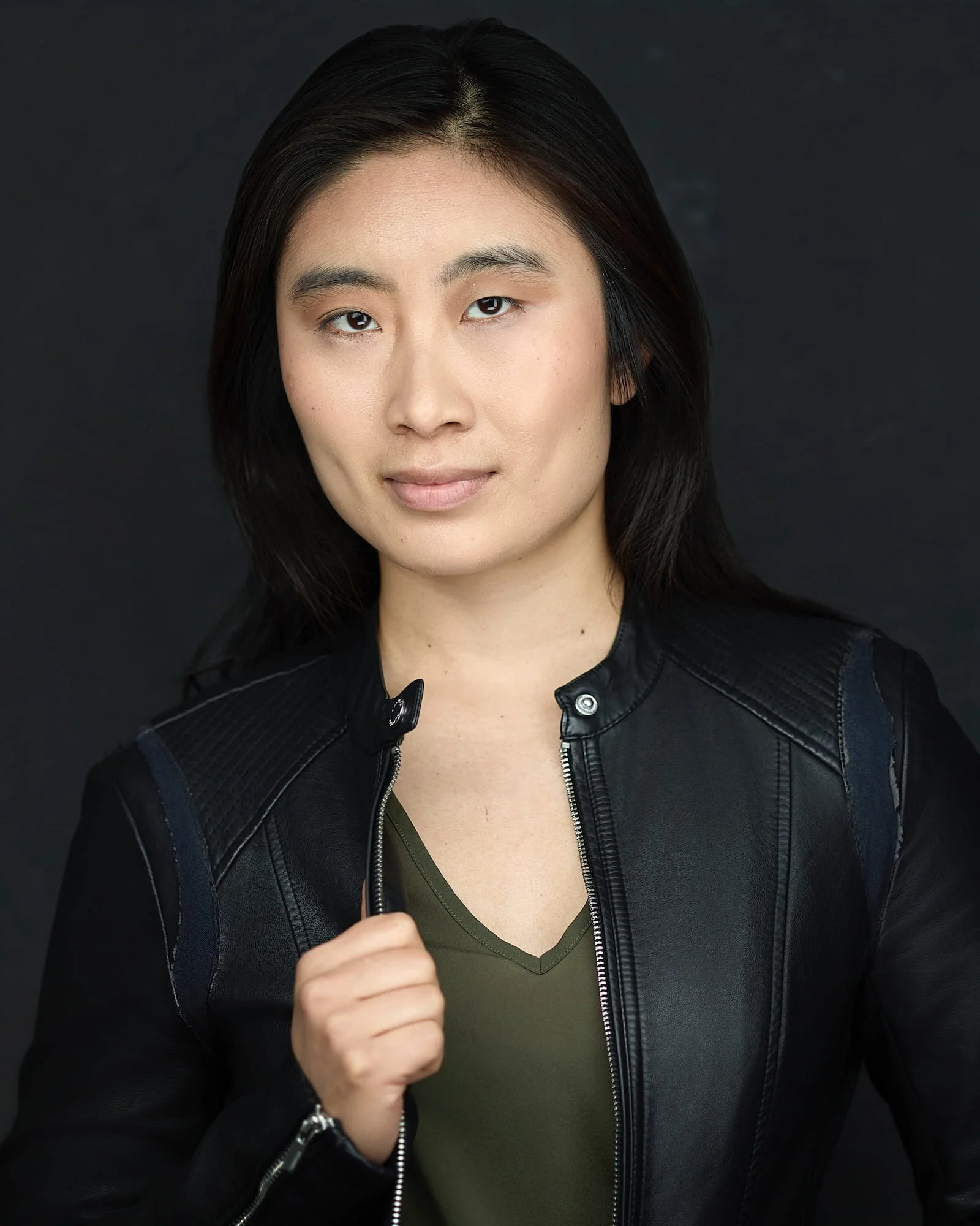 Theatrical actress headshot of an asian woman wearing a green shirt and black leather jacket
