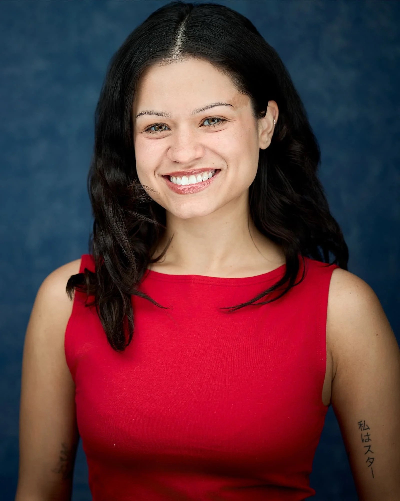 Actress headshot a young female wearing a red shirt photographed against a blue backdrop