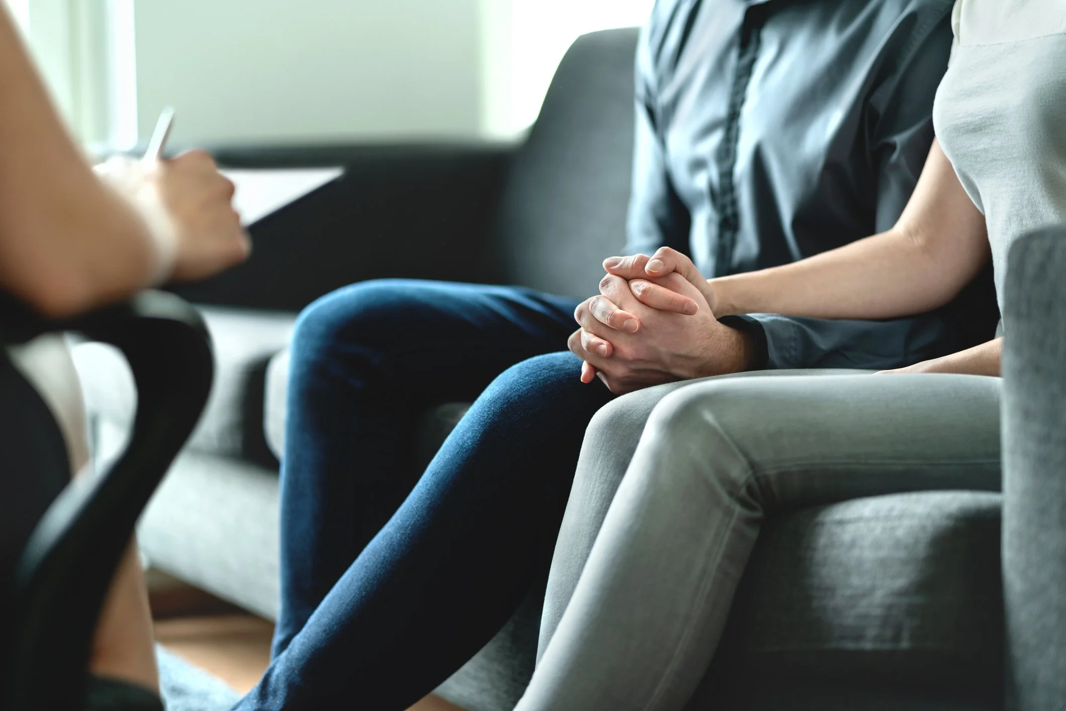 People sitting on a couch during a therapy session with a counselor taking notes.