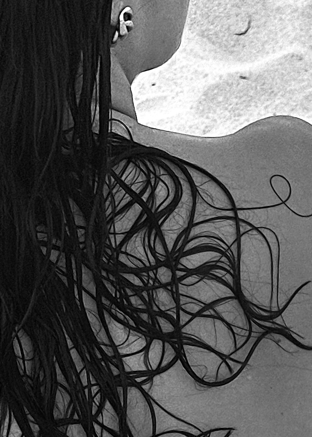 Close-up, black and white photo of a woman's shoulder, part of her face, earring, and tangled wet hair.