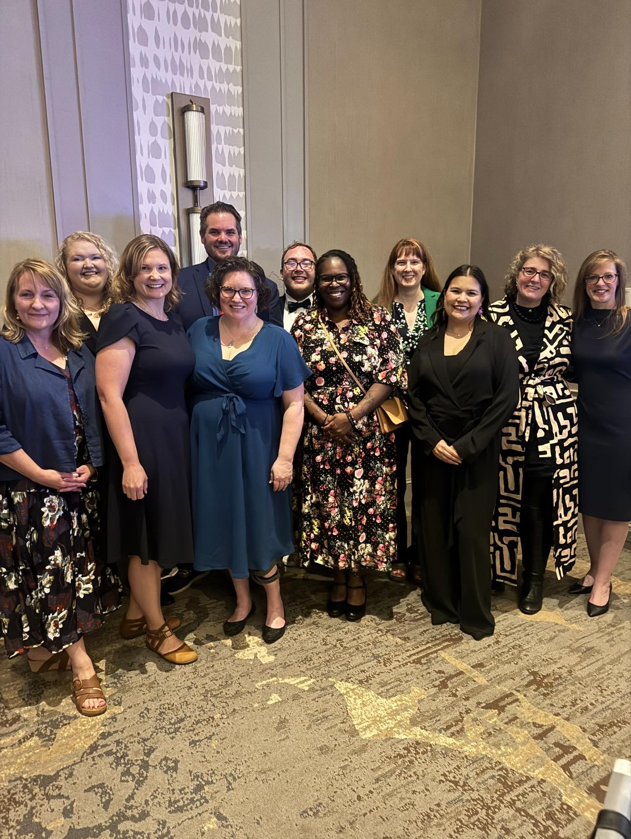 Group of ten people posing for a photo at an indoor event.