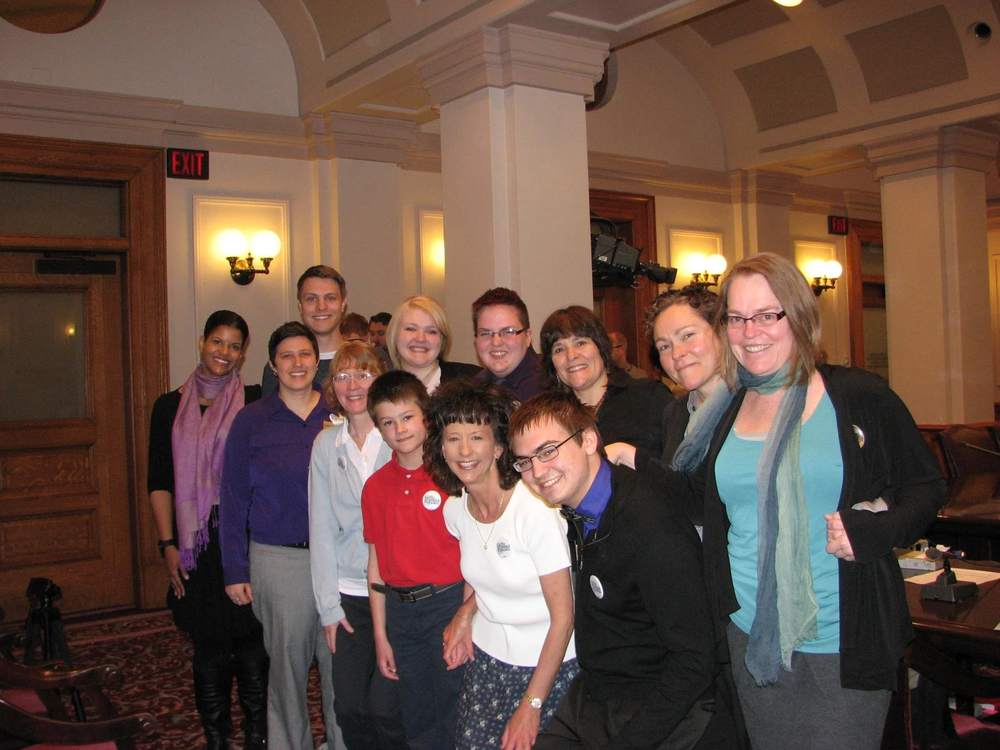 A group of diverse people standing together, smiling, indoors in a formal setting.