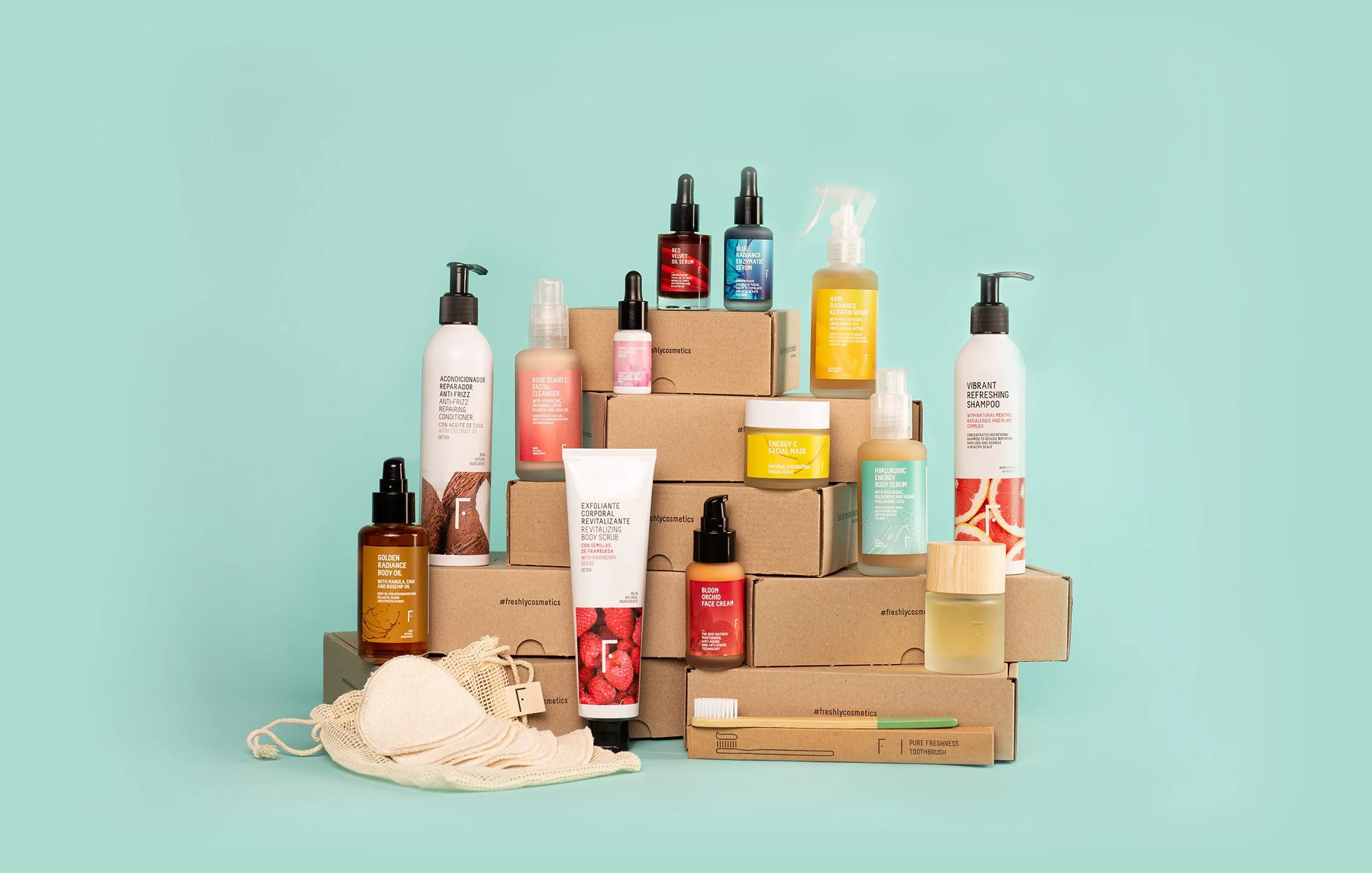 Collection of skincare and beauty products displayed on cardboard boxes against a mint green background, including serums, sprays, creams, a toothbrush, and reusable cloths.