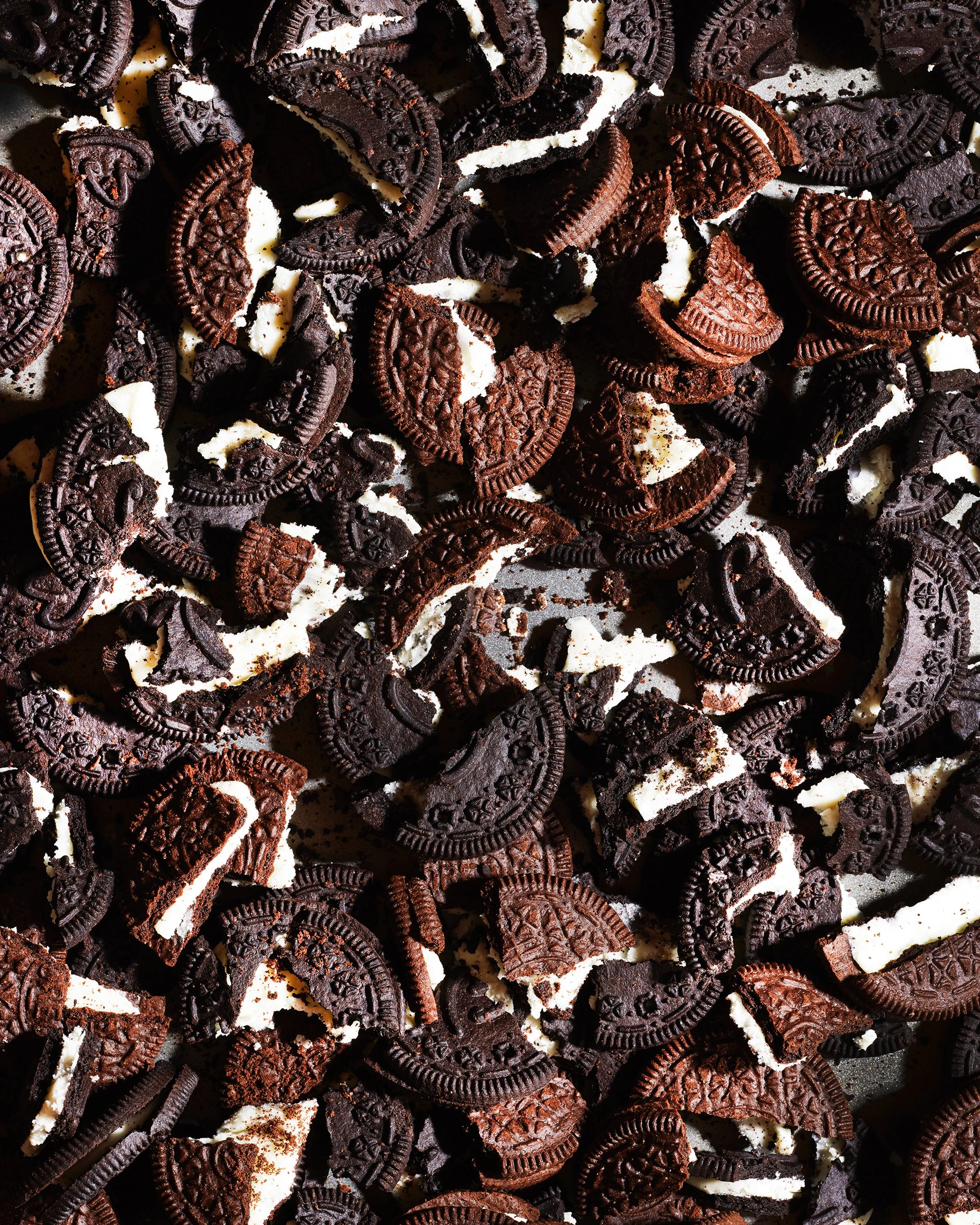 Broken Oreo cookies with cream filling scattered across a surface.