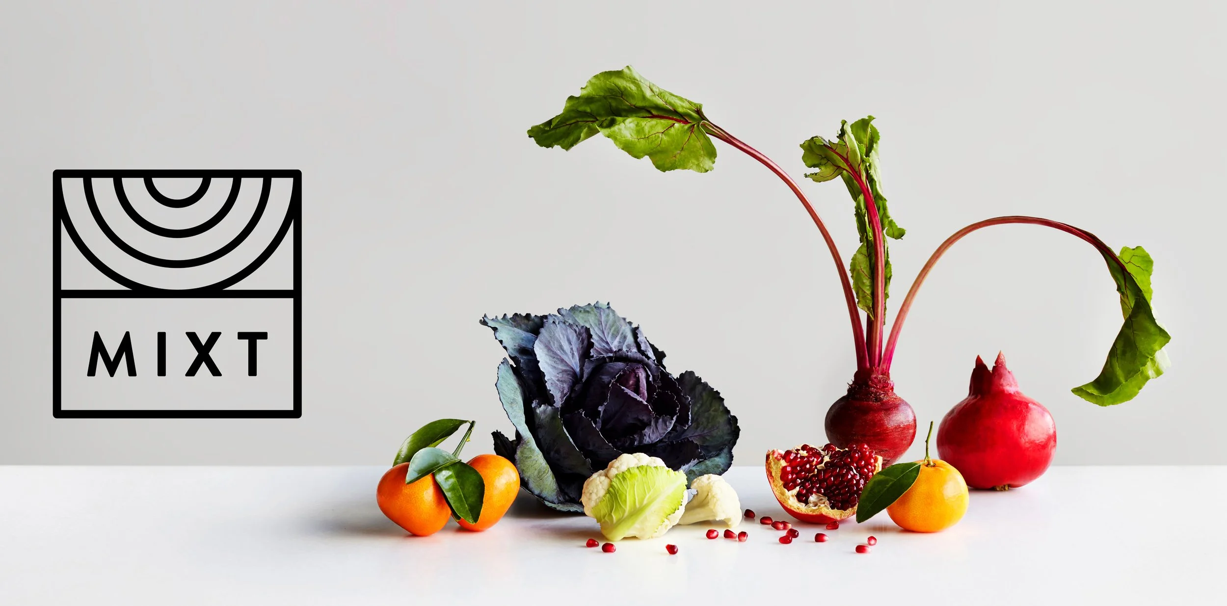 A collection of vegetables and fruits on a white surface, including radishes with green leaves, cabbage, cauliflower, pomegranate, tangerines with green leaves, and a block of tofu, with a black and white logo for MIXT.