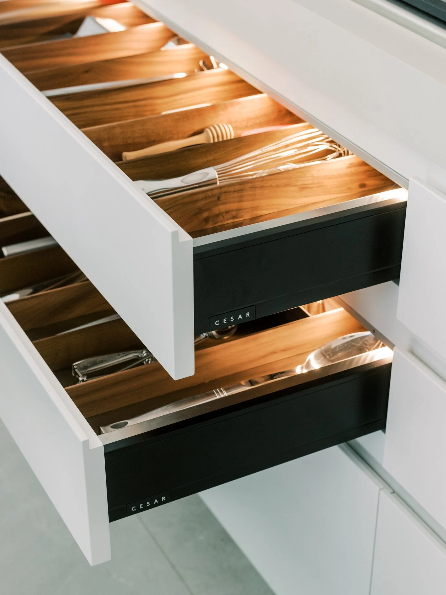 Open kitchen drawers with luxe wooden inserts containing elegant flatware