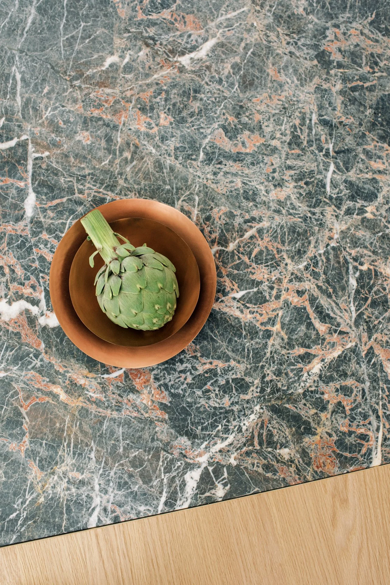 Artichoke in copper bowl on marble surface