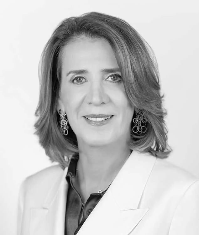 Black and white portrait of a woman with shoulder-length hair wearing earrings and a white blazer.