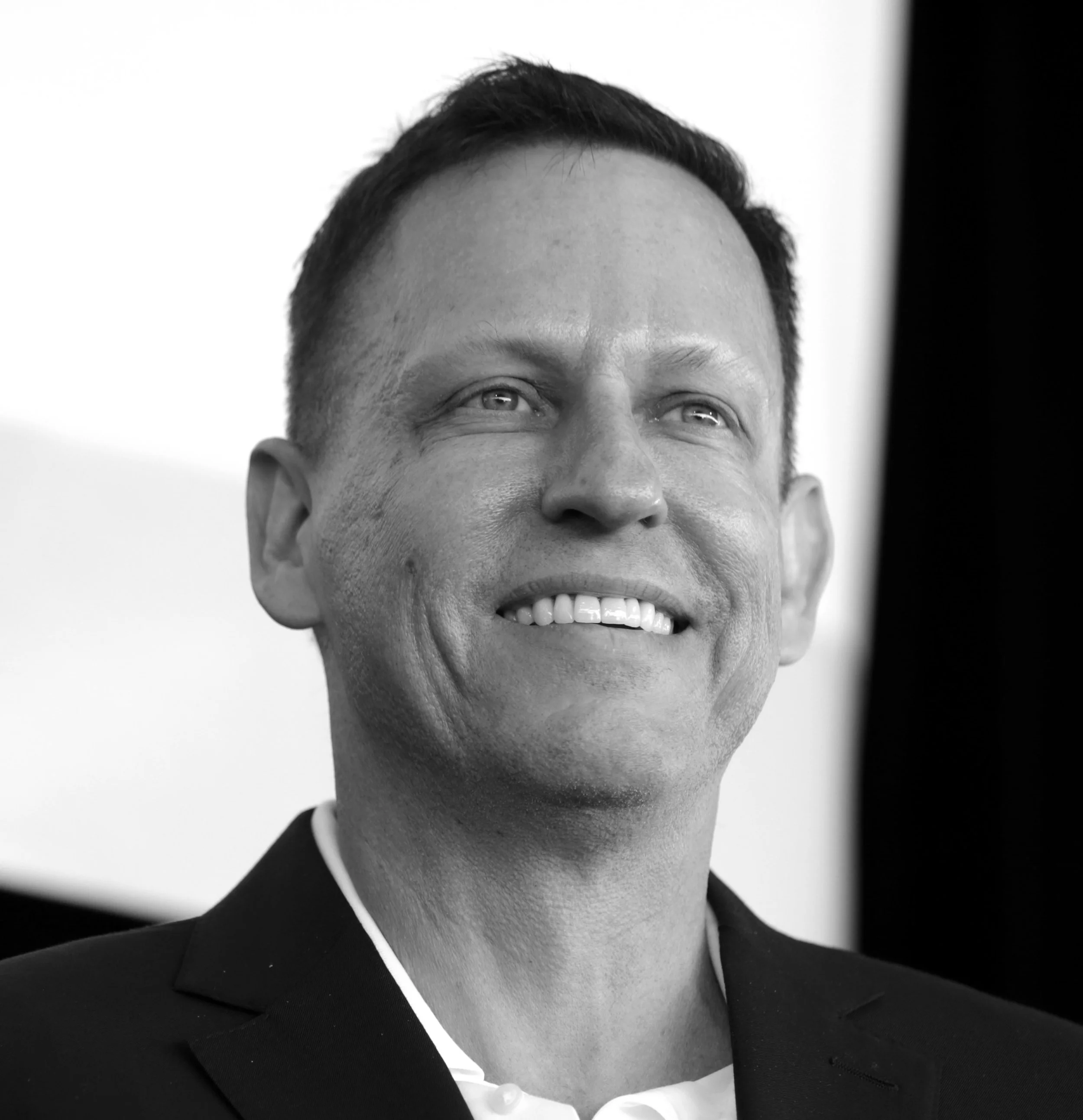 Close-up of a smiling man in a suit, black and white photograph.