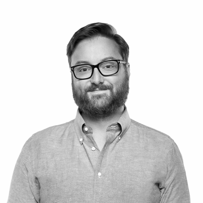 Black and white portrait of a man with glasses, a beard, and wearing a button-down shirt.