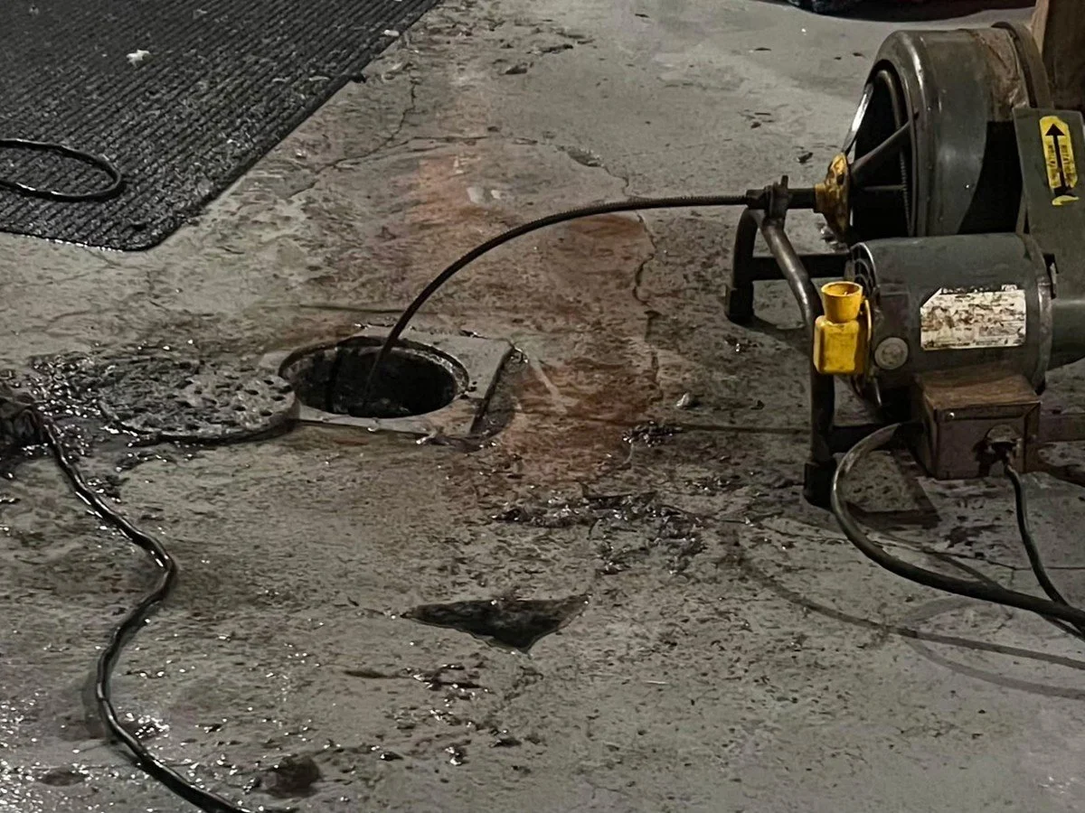 Professional sewer-cleaning machine clearing a commercial floor drain.