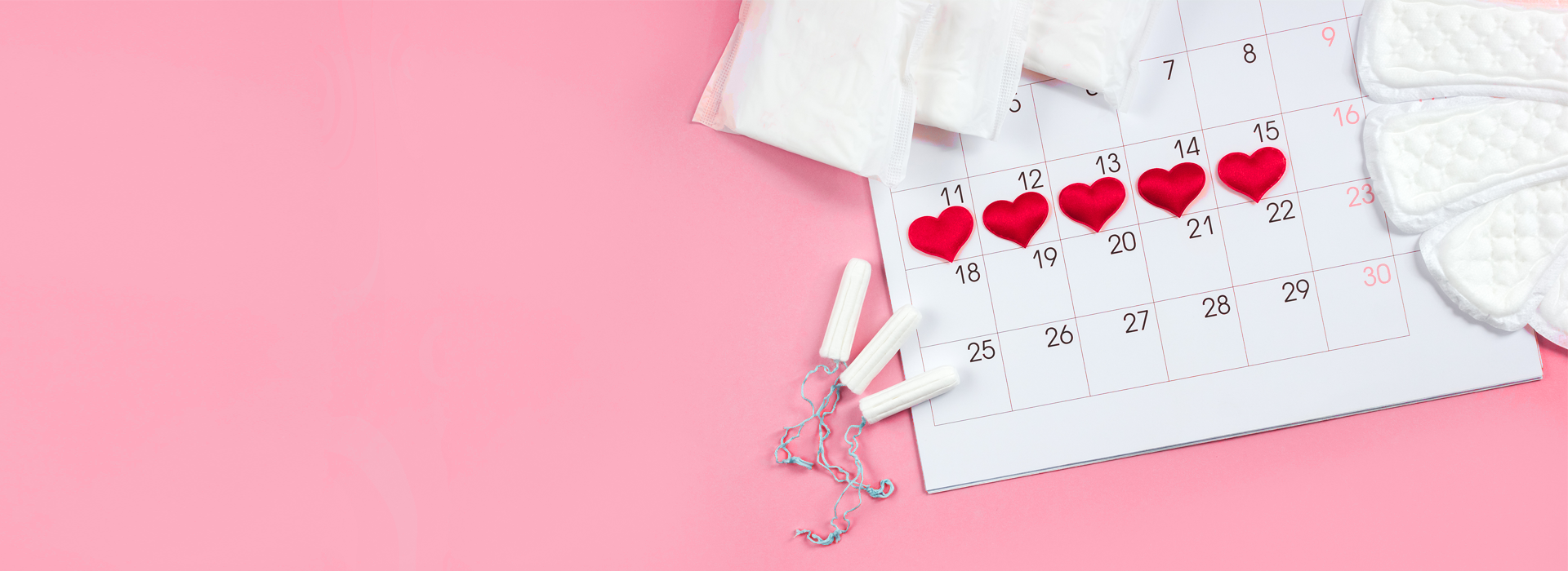 Calendar on pink background with red heart-shaped markers on days 11, 12, 13, 14, and 15, and menstrual pads and tampons nearby.