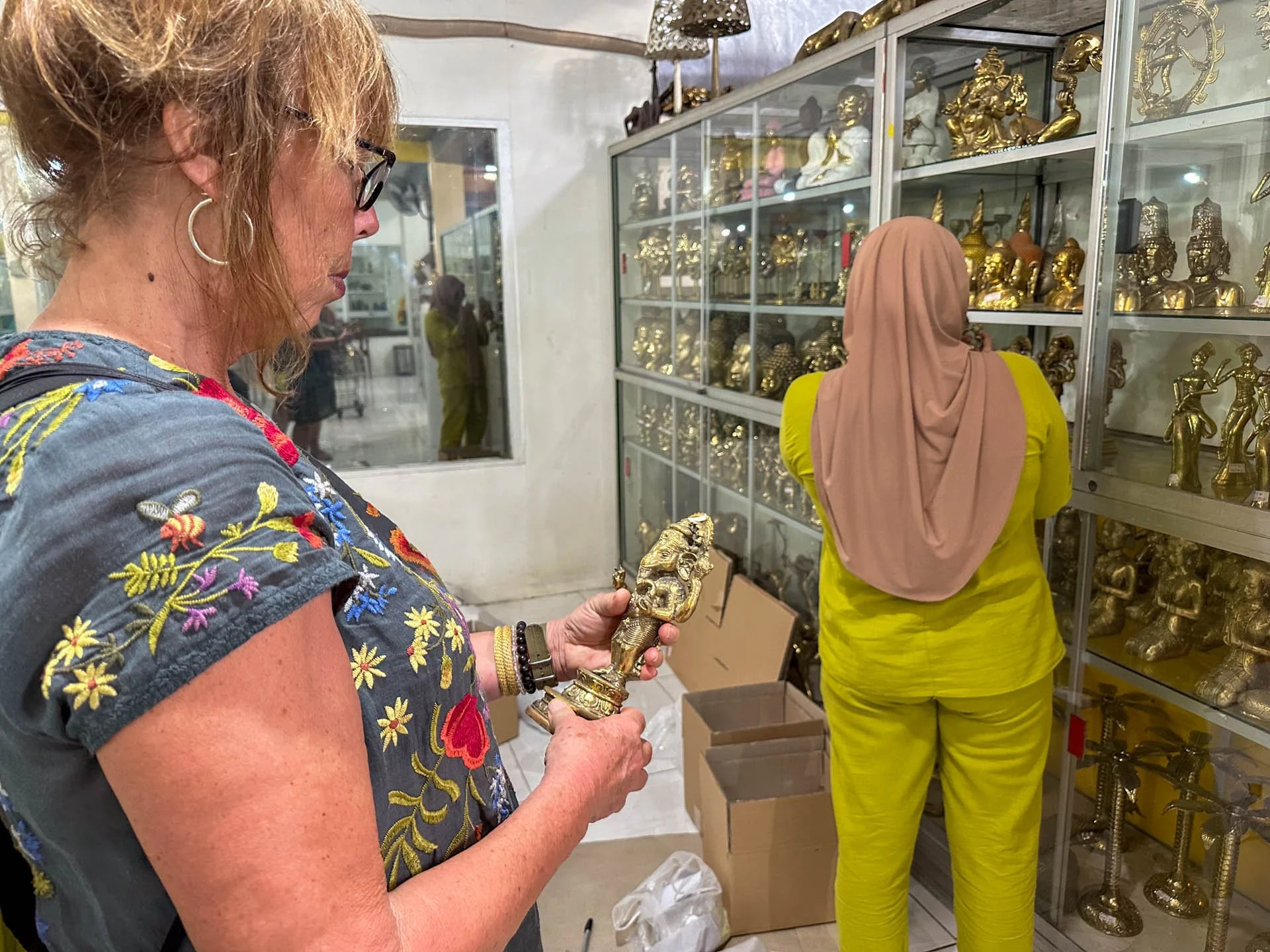 Caravan Gallery in La Conner, WA - Owner Linda Banaszak shopping for decorative golden figurines in a store in Bali. 
