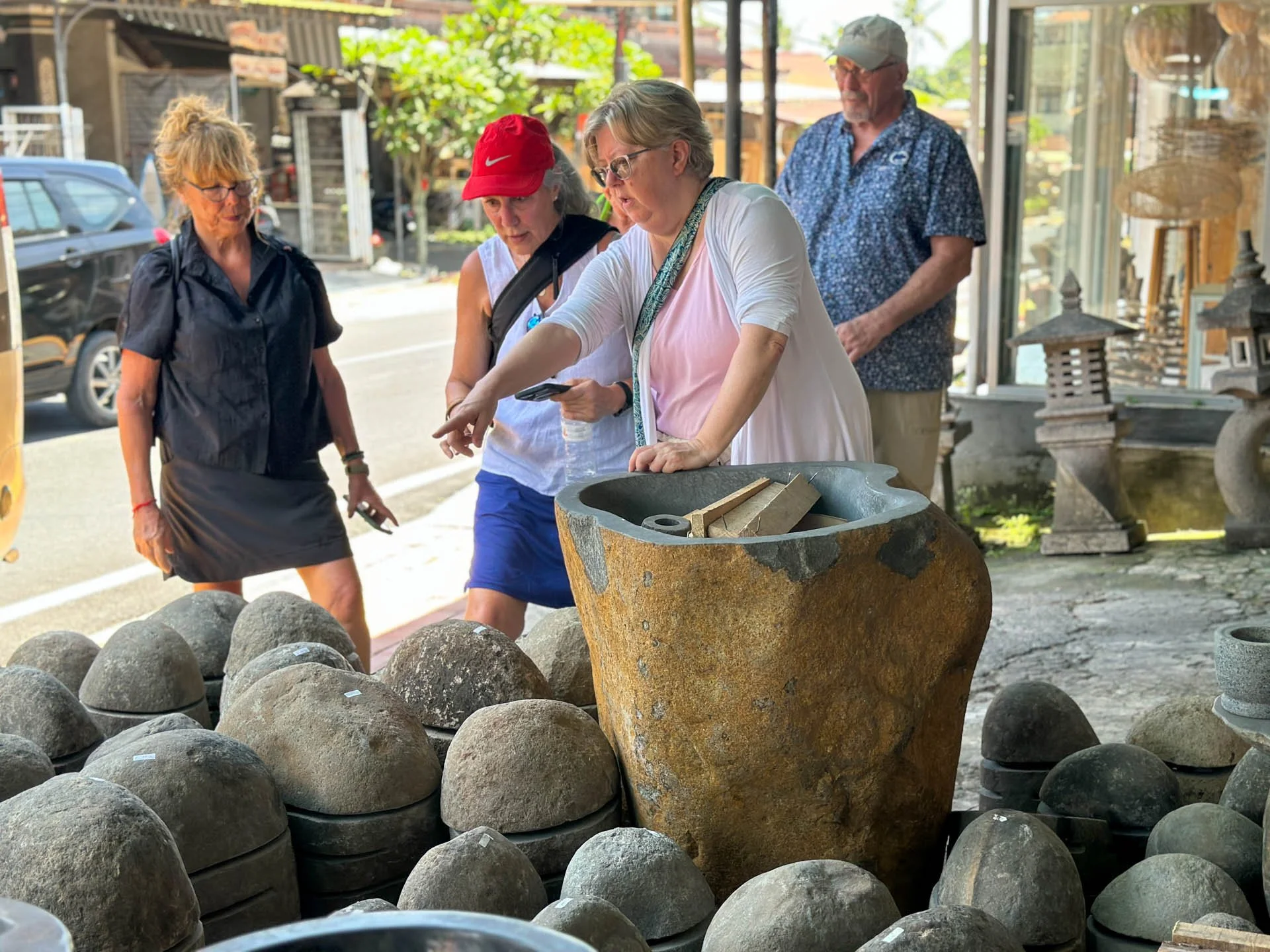 Caravan Gallery in La Conner, WA - Owner Linda Banaszak shopping for outdoor stoneware, including stones, a large urn, and lanterns, inside a store with large glass windows.