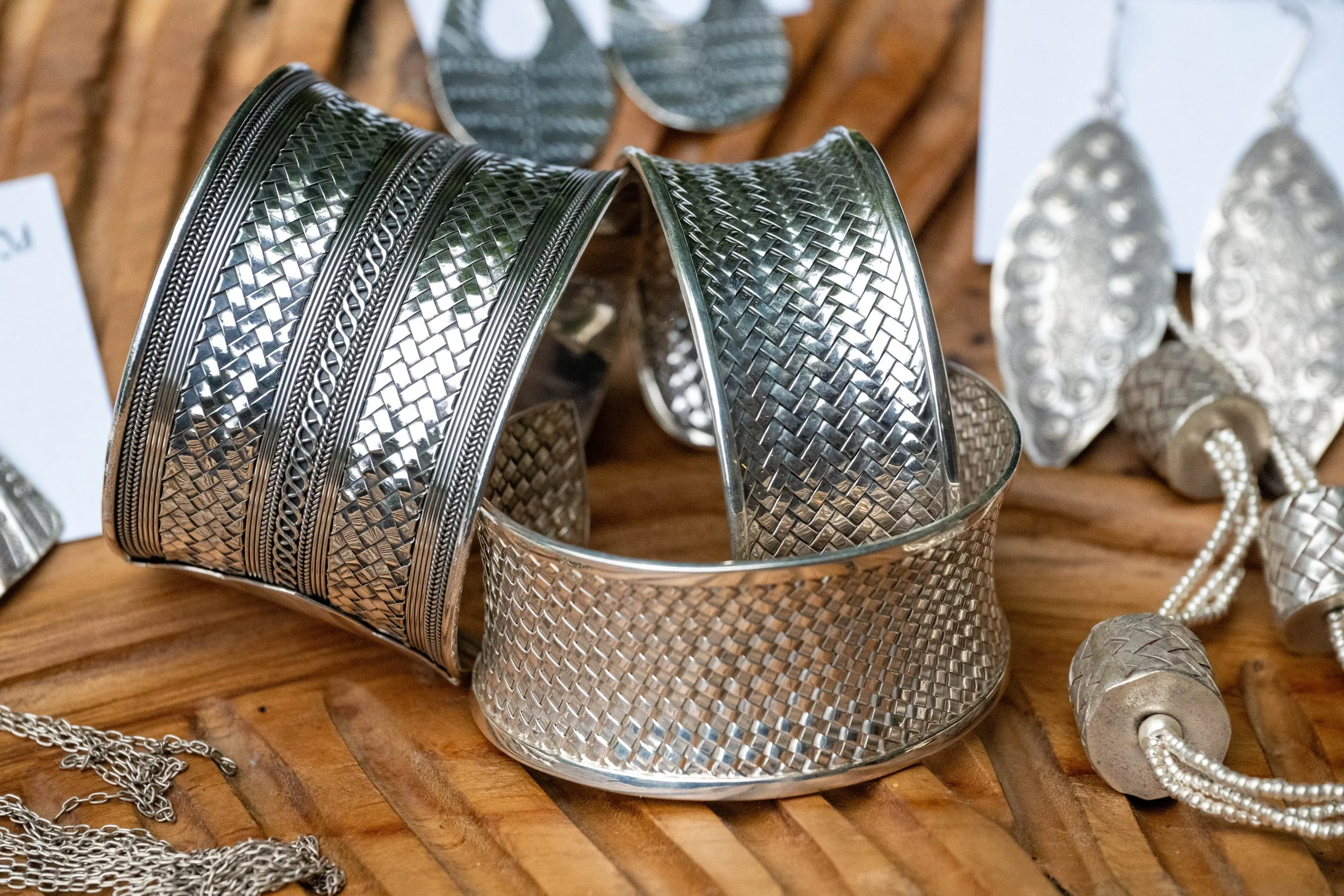 Caravan Gallery in La Conner, WA - Silver jewelry including statement bracelets, rings, and necklaces with textured and intricate designs displayed on a wooden surface.
