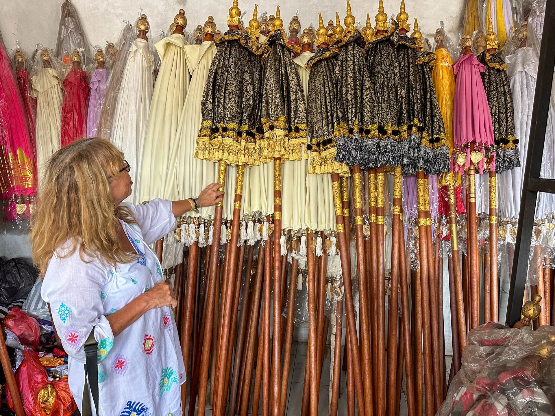 Caravan Gallery in La Conner, WA - Owner Linda Banaszak shopping for colorful umbrellas in a market in Bali. The umbrellas are decorated with gold, black, pink, and purple designs, with long wooden handles.