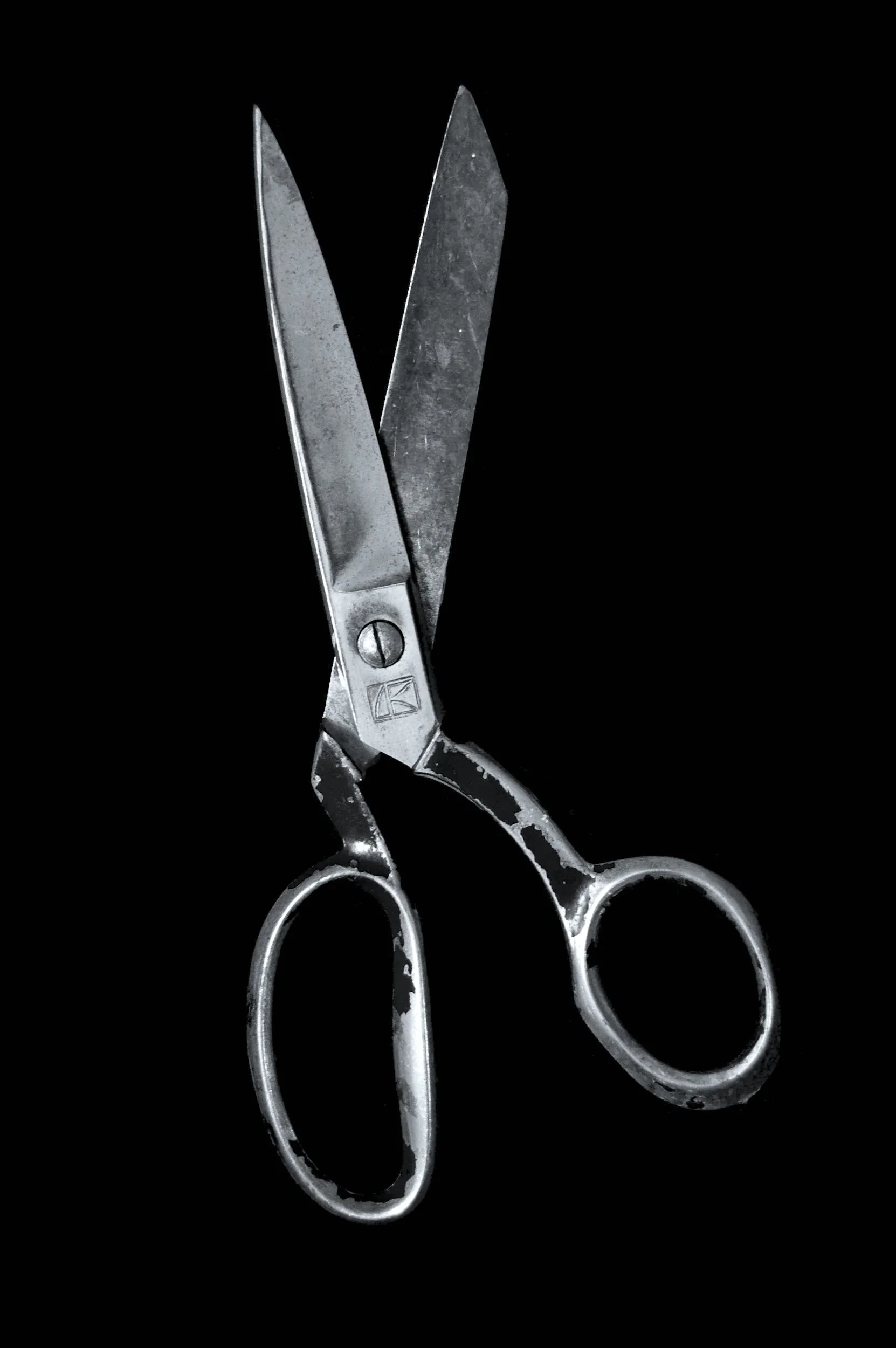 A pair of vintage scissors with metal blades and handles, set against a black background.