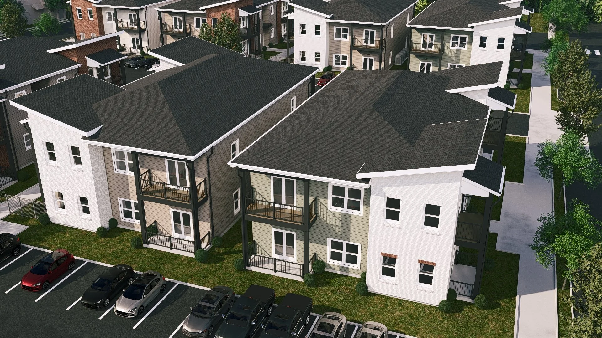 An aerial view of a modern multi-unit residential complex with parking spaces, green lawns, and sidewalks, featuring white and beige two-story buildings with black balconies and dark gray roofs.