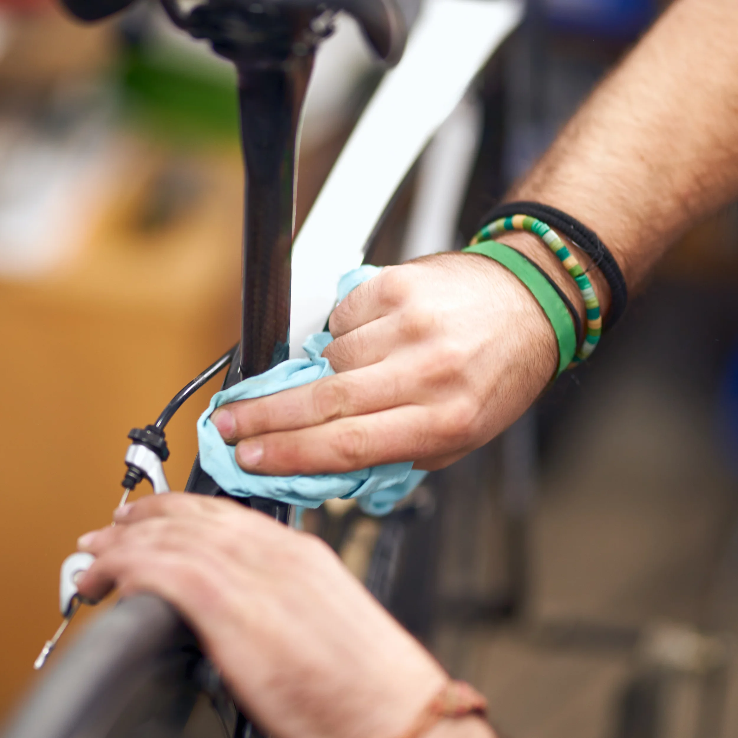 Person cleaning a bicycle frame with a cloth.