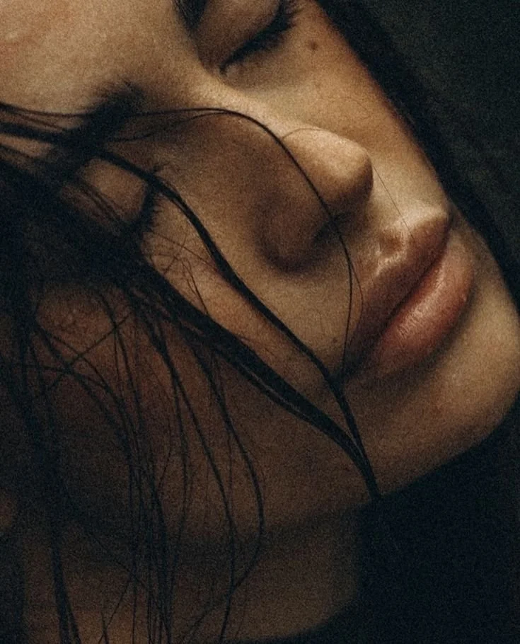 Close-up of a woman with eyes closed, wet hair covering part of her face, and a soft, relaxed expression.