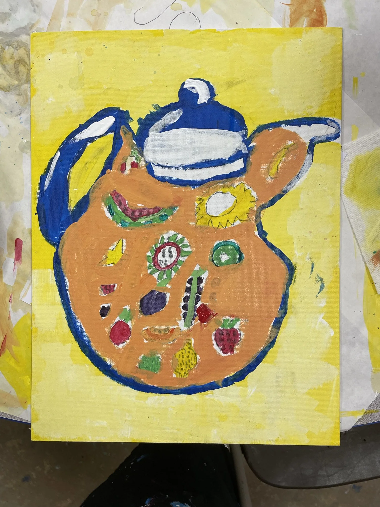 A brightly colored painting of a teapot with a yellow background. The teapot's body is filled with various small, colorful illustrations of fruits and vegetables, giving it a whimsical appearance.