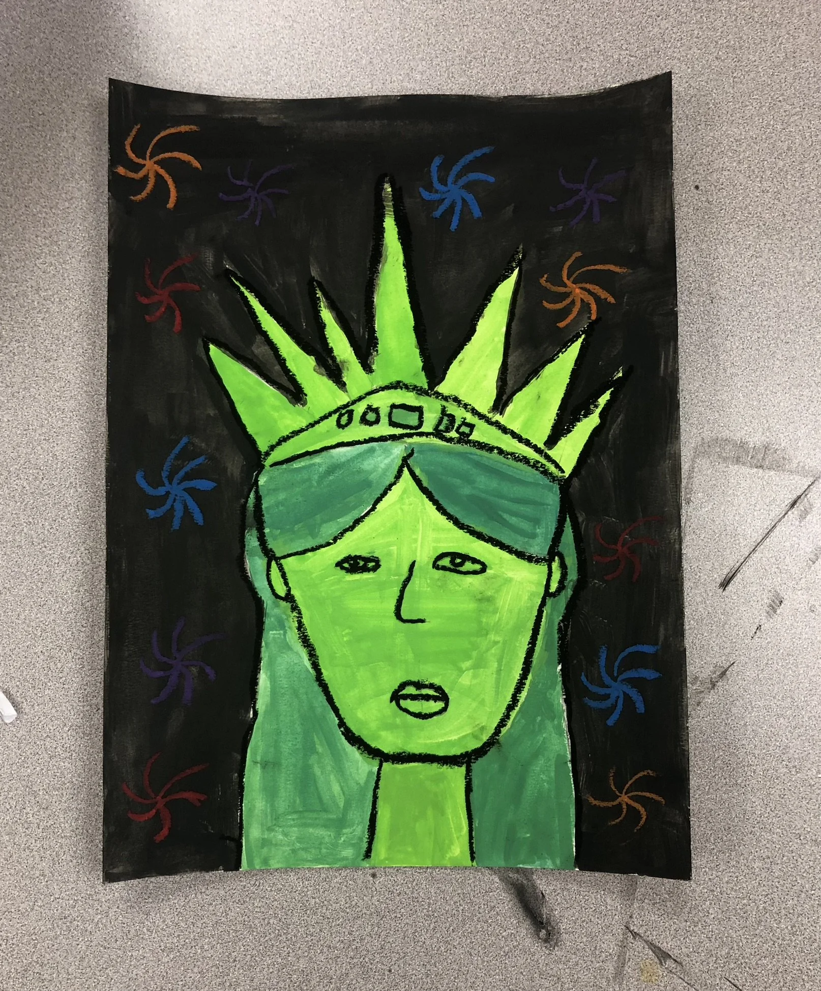 Colorful drawing of the Statue of Liberty with a green face and crown, wearing sunglasses, on a black background with multicolored swirl patterns.
