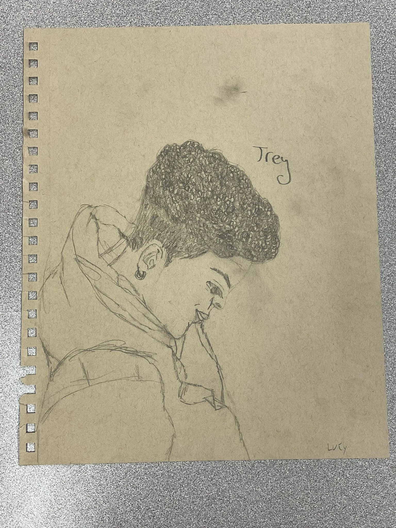 A pencil sketch on a yellowed piece of paper of a woman with curly hair looking downward, wearing a hoodie and earrings. The name 'Trey' is written above her. The artist's signature 'LUCY' is in the bottom right corner.