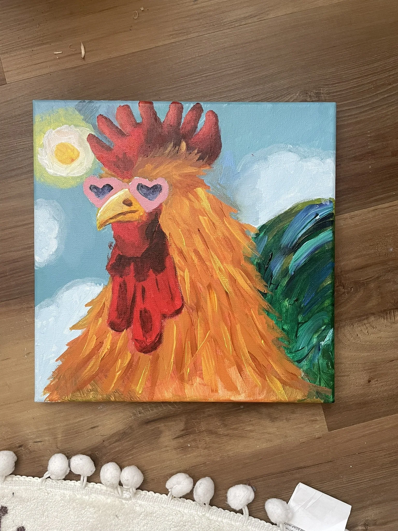 Colorful painting of a rooster wearing pink heart-shaped sunglasses, with a blue sky, clouds, and a sun in the background.