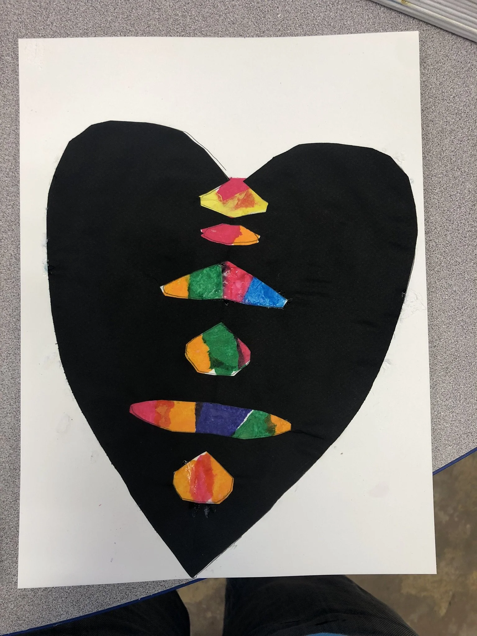 A heart-shaped collage with various colorful paper pieces inside, set against a white background.