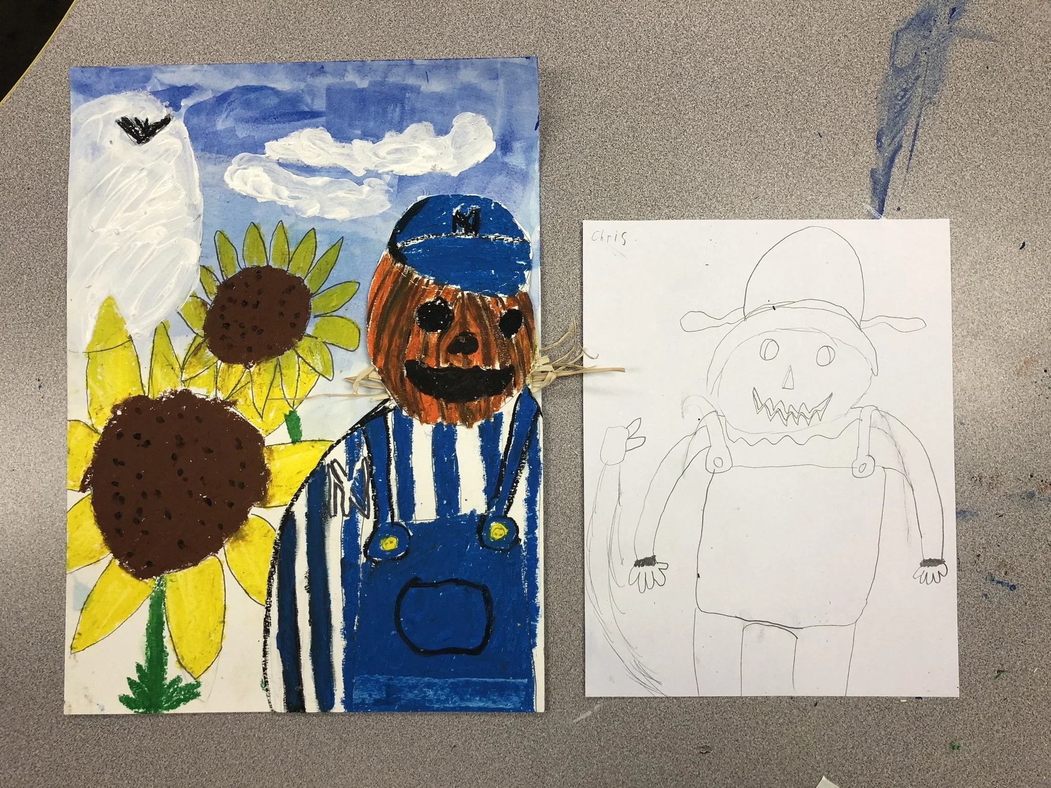 Child's colorful painting of a pumpkin-headed scarecrow with sunflower plants, a blue sky with clouds, and a black bird flying, next to a pencil sketch of a similar scarecrow figure.