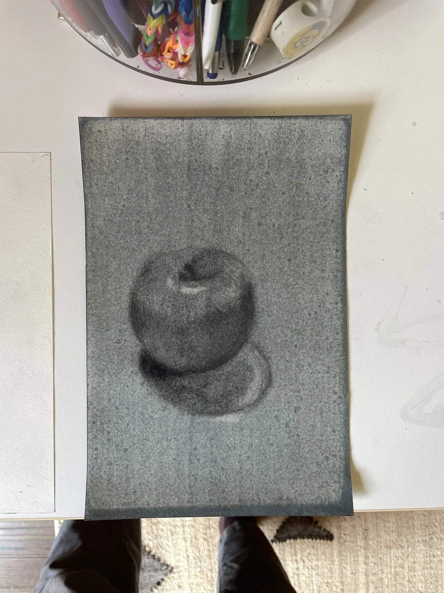 A monochrome artwork of a still life painting depicting two apples, one larger and one smaller, set on a surface with a plain background.