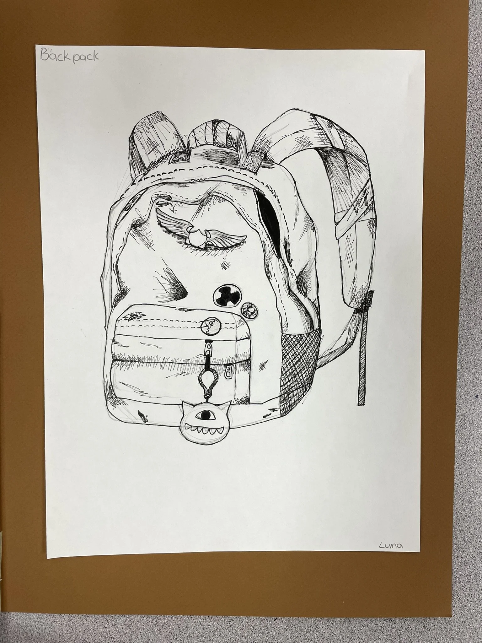 Black and white drawing of a backpack with a cute monster face, a small monster keychain, and various patches and buttons on the front pocket.