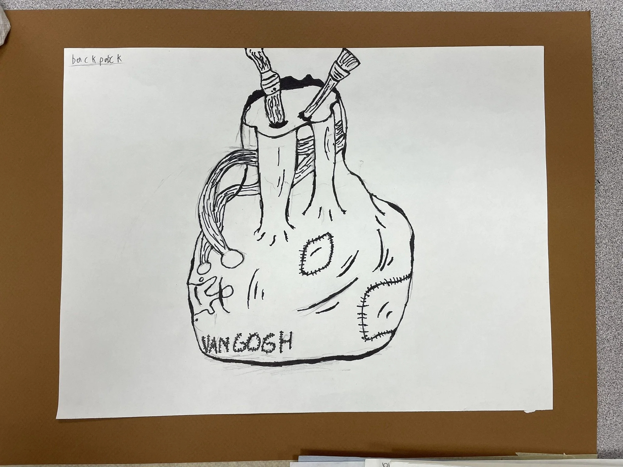 Line drawing of a backpack with a heart and the words "VAN GOGH" on it, with two pens inserted into the top opening. The backpack and pens are on a white sheet of paper placed on a brown surface.