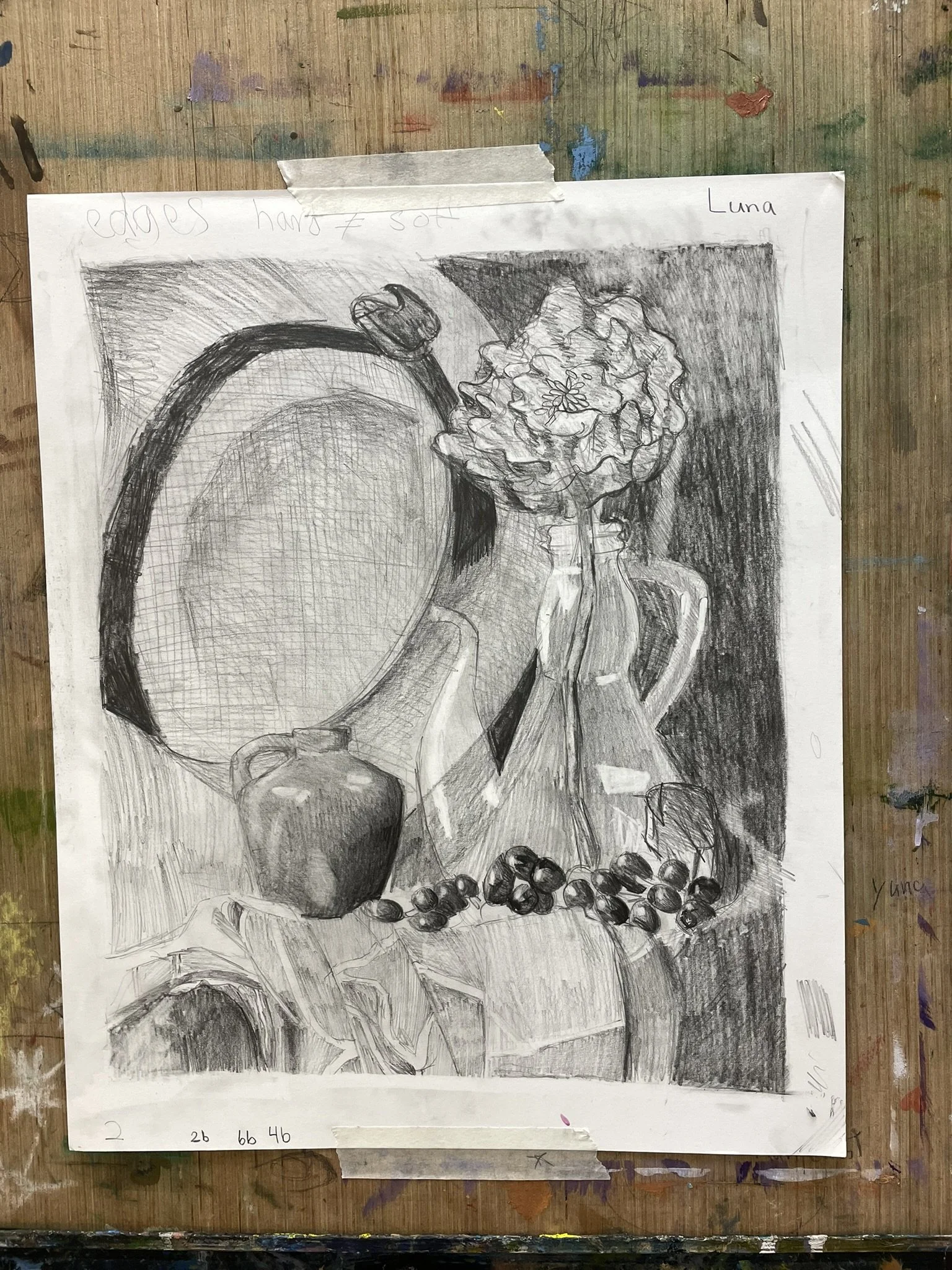 Black and white pencil sketch of various objects including a large round mirror, a flower in a jug, an apple, grapes, and a cloth-covered table, labeled 'Luna' at the top right corner.