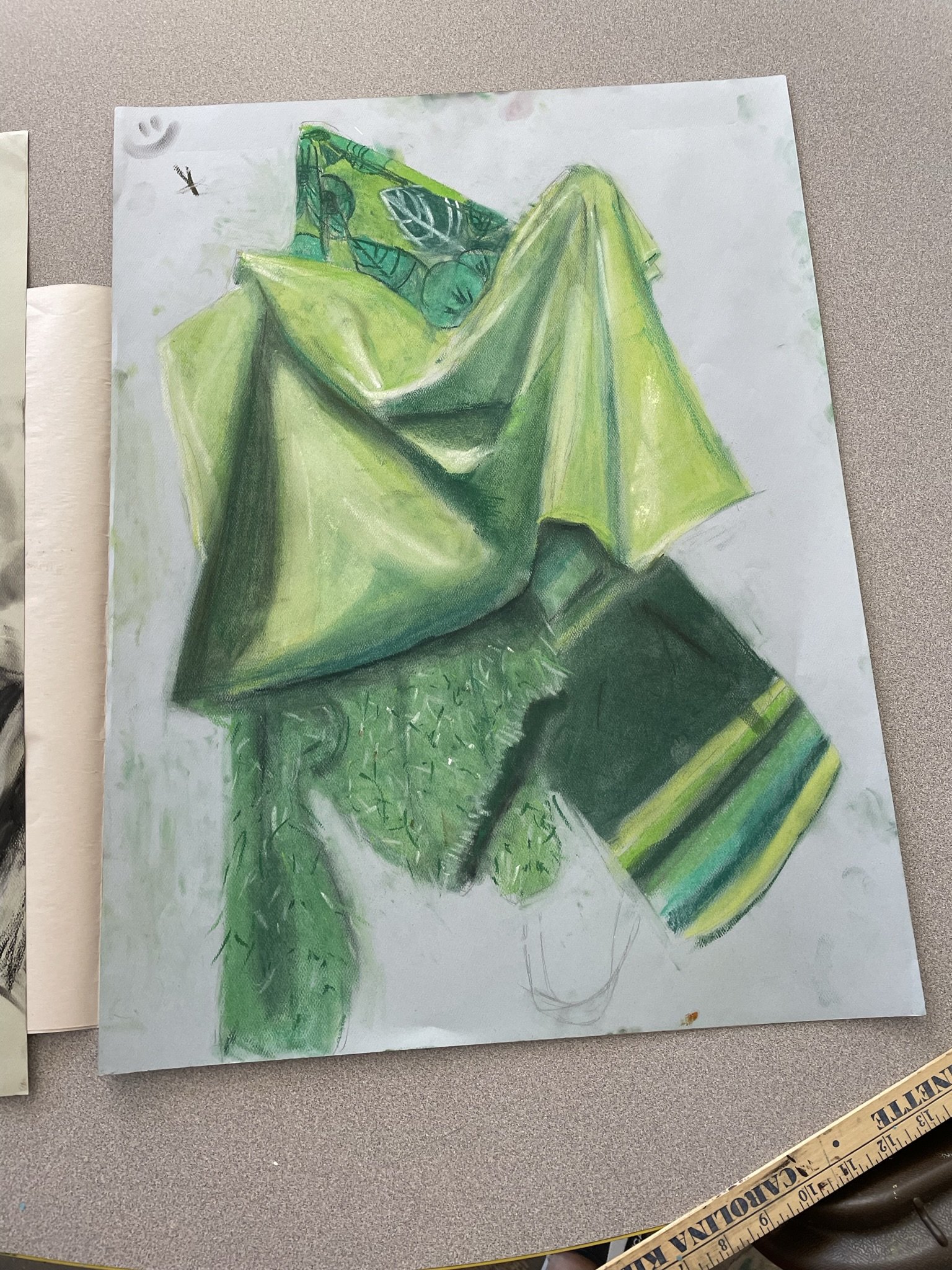 A colorful drawing of a green dragon with spiky details on its back, sitting on a surface with a green and black striped object nearby.