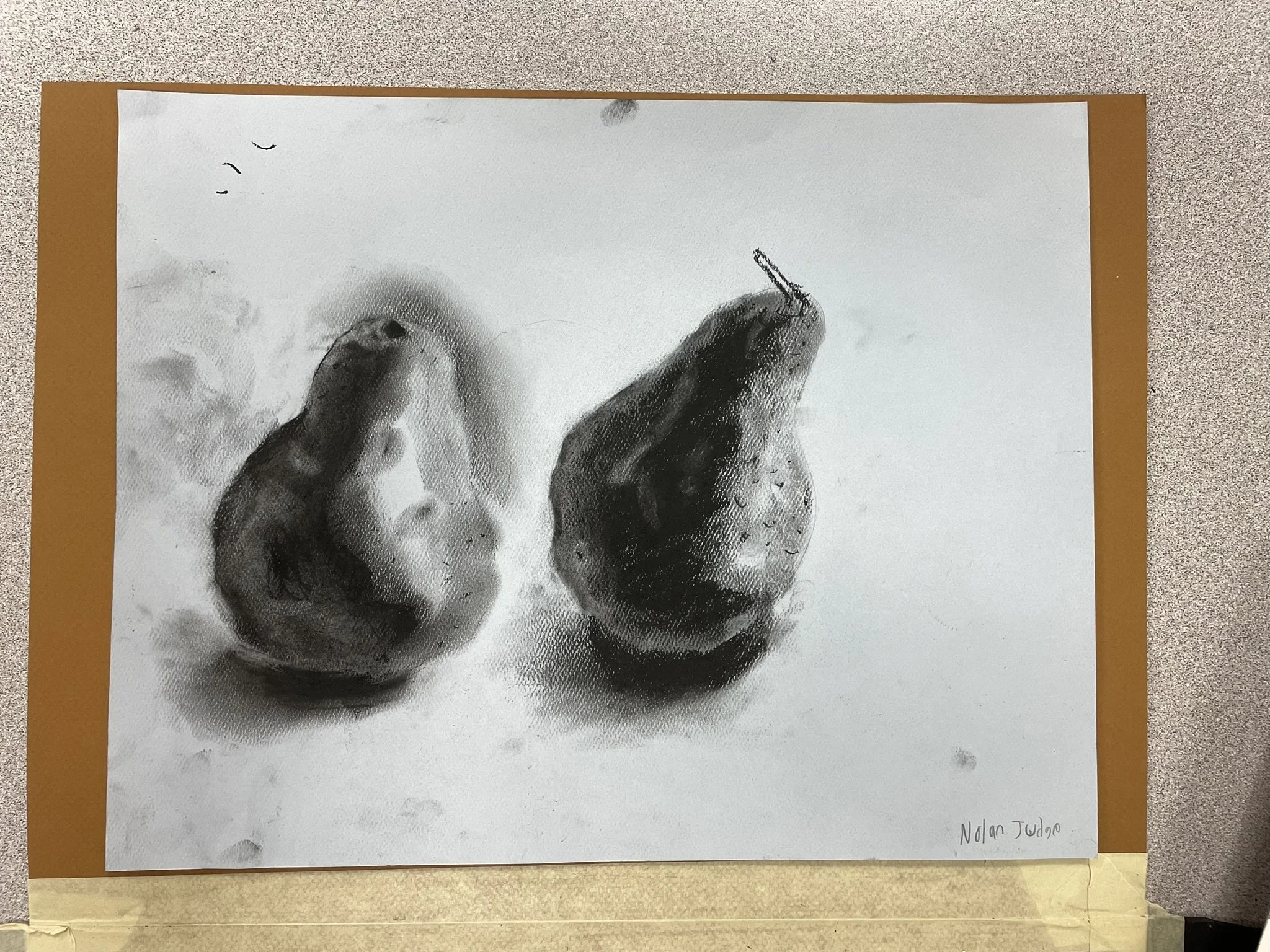 Black and white drawing of two pears on a surface with a textured background. One pear has a stem, the other does not. The signature 'Nolan Juarez' is in the bottom right corner.