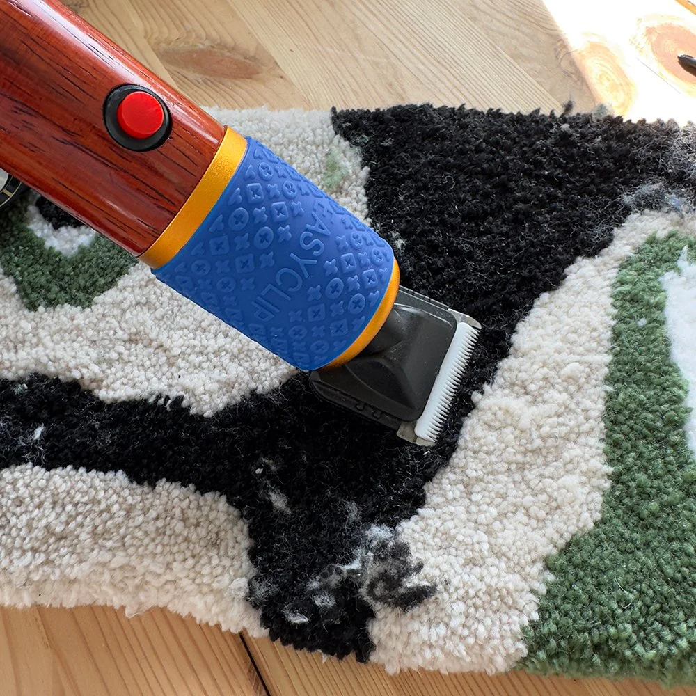 Carpet carver with a wooden handle and a blue grip is cleaning a multicolored shaggy carpet on a wooden floor.