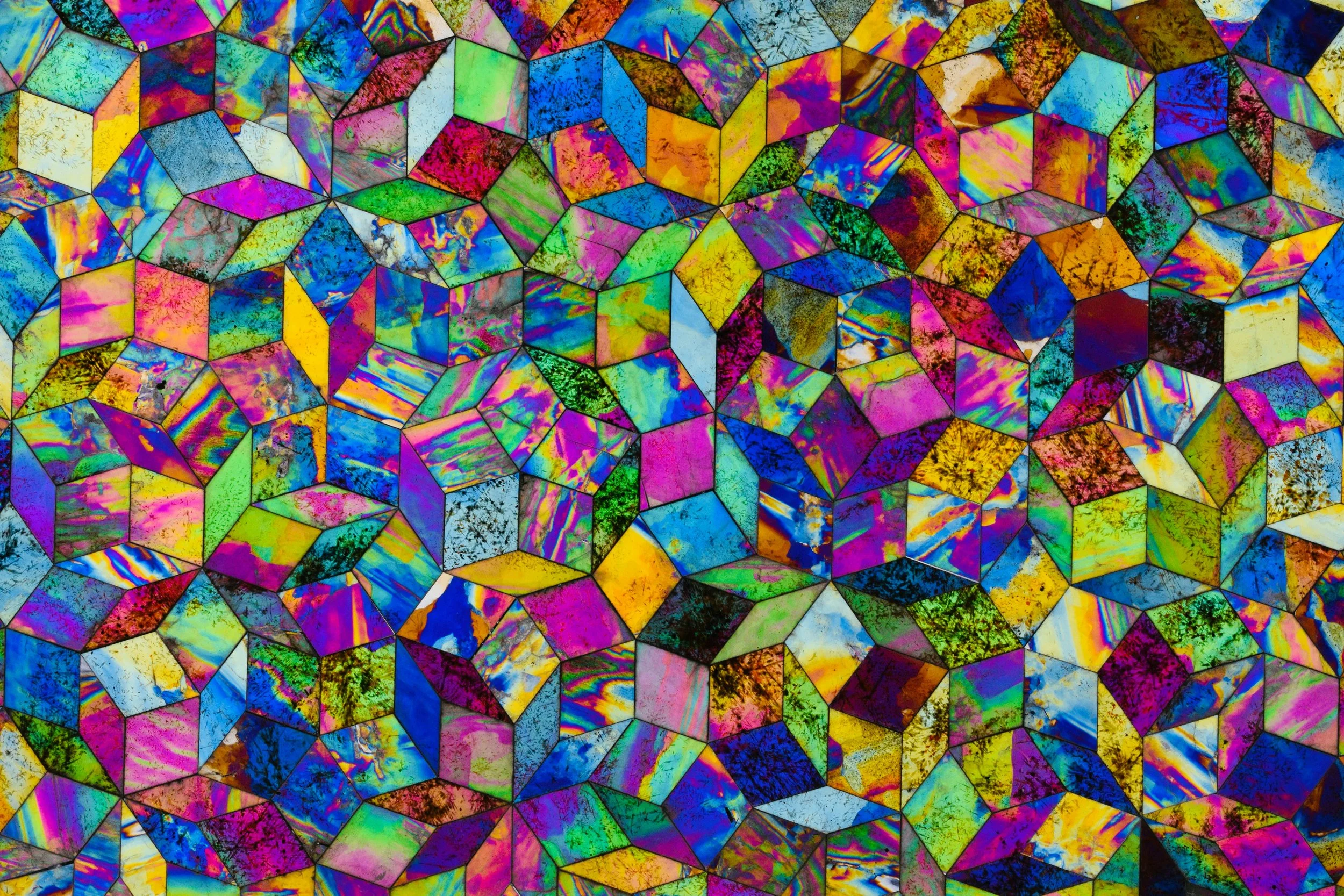 A colorful mosaic composed of numerous irregularly shaped, brightly colored glass pieces with iridescent and marbled patterns.