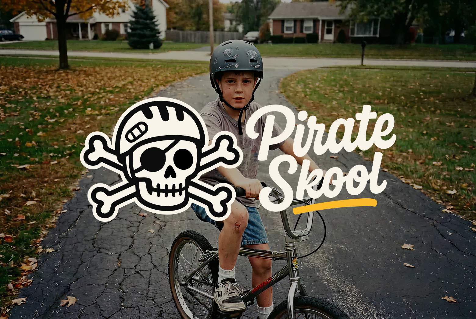 A young boy wearing a bike helmet on a bicycle with a scrape on his knee, standing on a suburban street, with Fall leaves on the ground, overlaid with a pirate skull and crossbones graphic and the words "Pirate Skool".