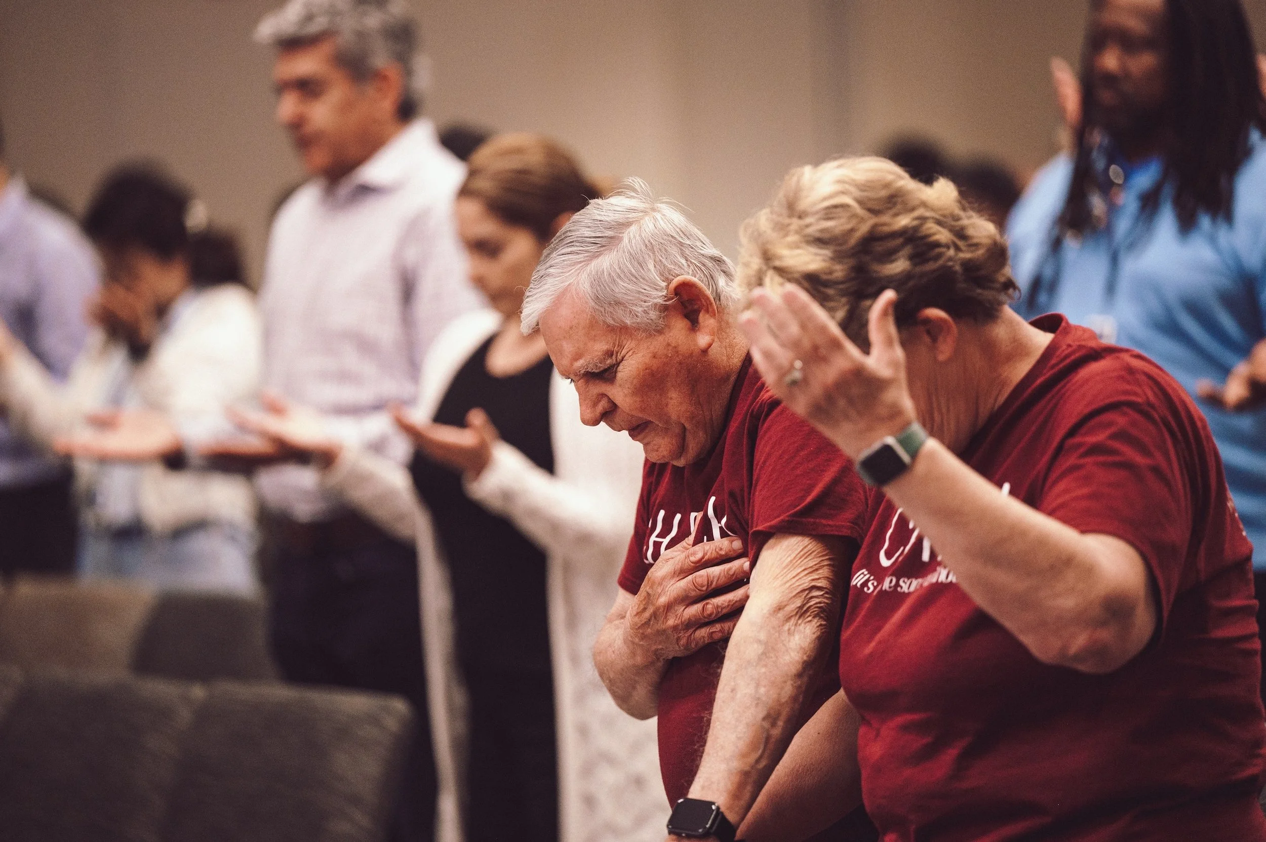 People praying with their hands on their chests in a church or prayer gathering.
