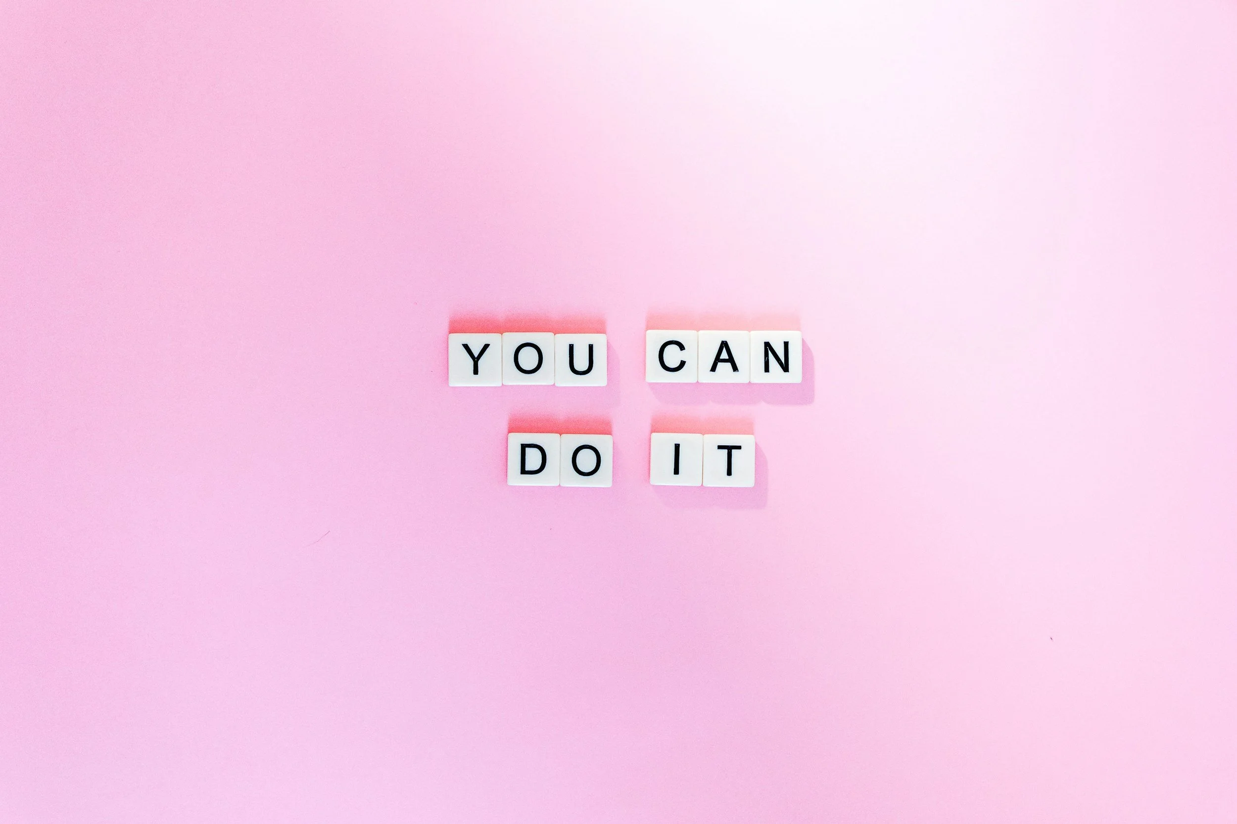 Pink background with white letter tiles spelling 'YOU CAN DO IT' arranged in three lines.