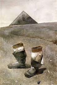 A pair of worn-out shoes with newspapers stuffed inside, placed on a dusty ground with the pyramid in the background.