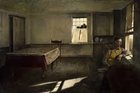 A young girl sitting on a couch in a dimly lit, old-fashioned room with wooden walls, a window with curtains, a bed, and a small table.