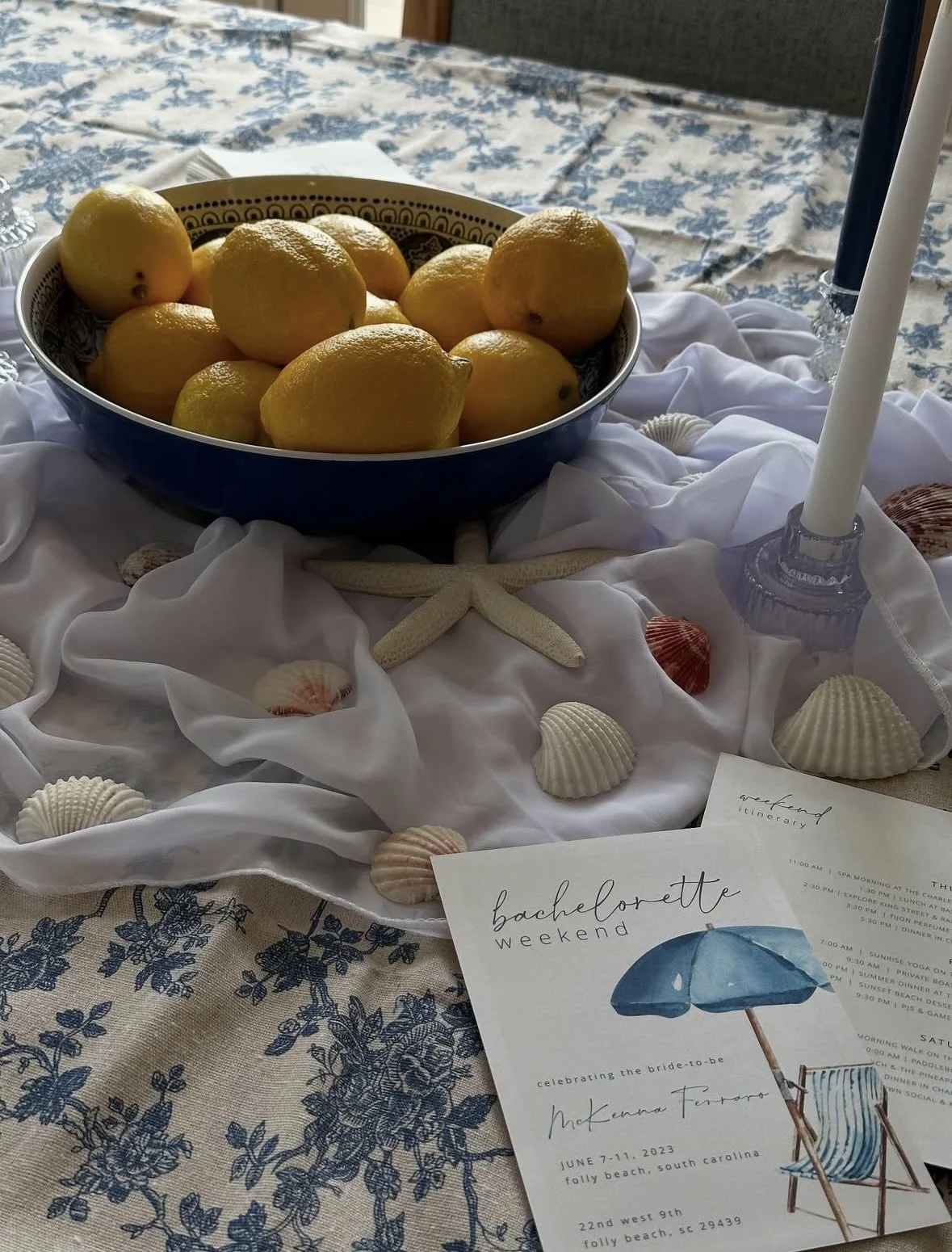 Lemon centerpiece on a table decorated with seashells, starfish, and candles, with a wedding itinerary and a blue and white beach-themed decor.