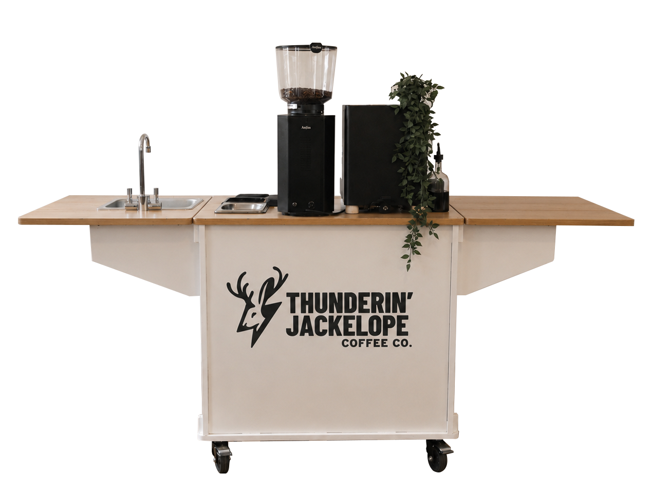 Coffee cart with wood countertop, coffee machine, a potted plant, and sink, branded with Thundering Jackalope Coffee Co. logo, on wheels.