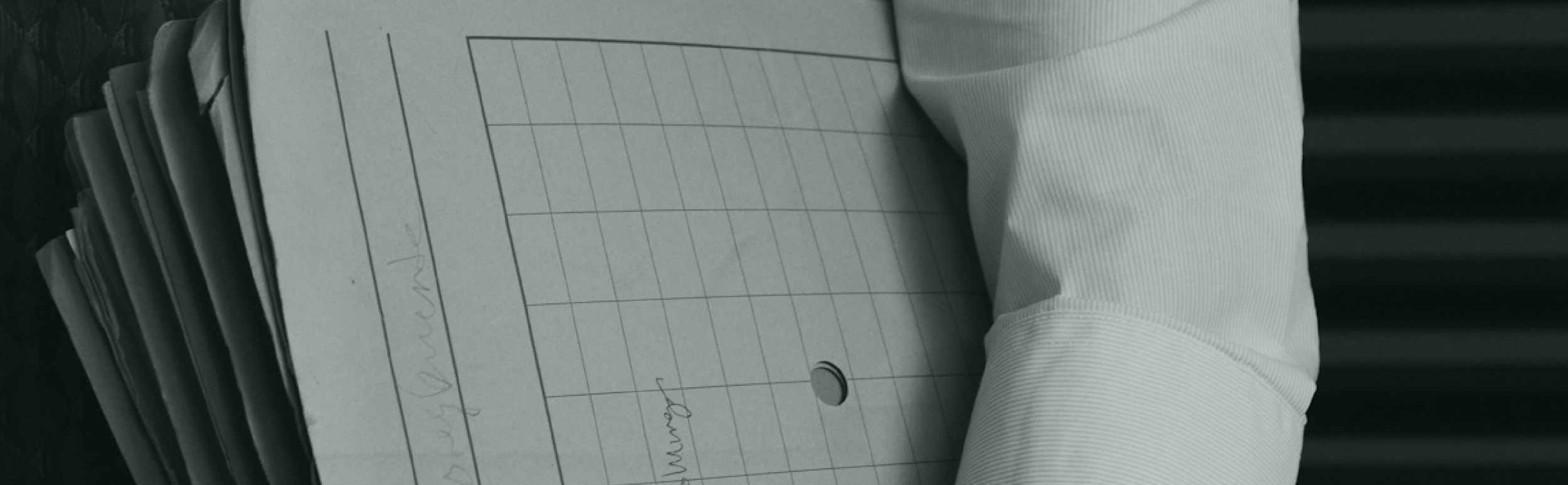 Stack of papers with handwriting, attached to a white sleeve or arm of a person.