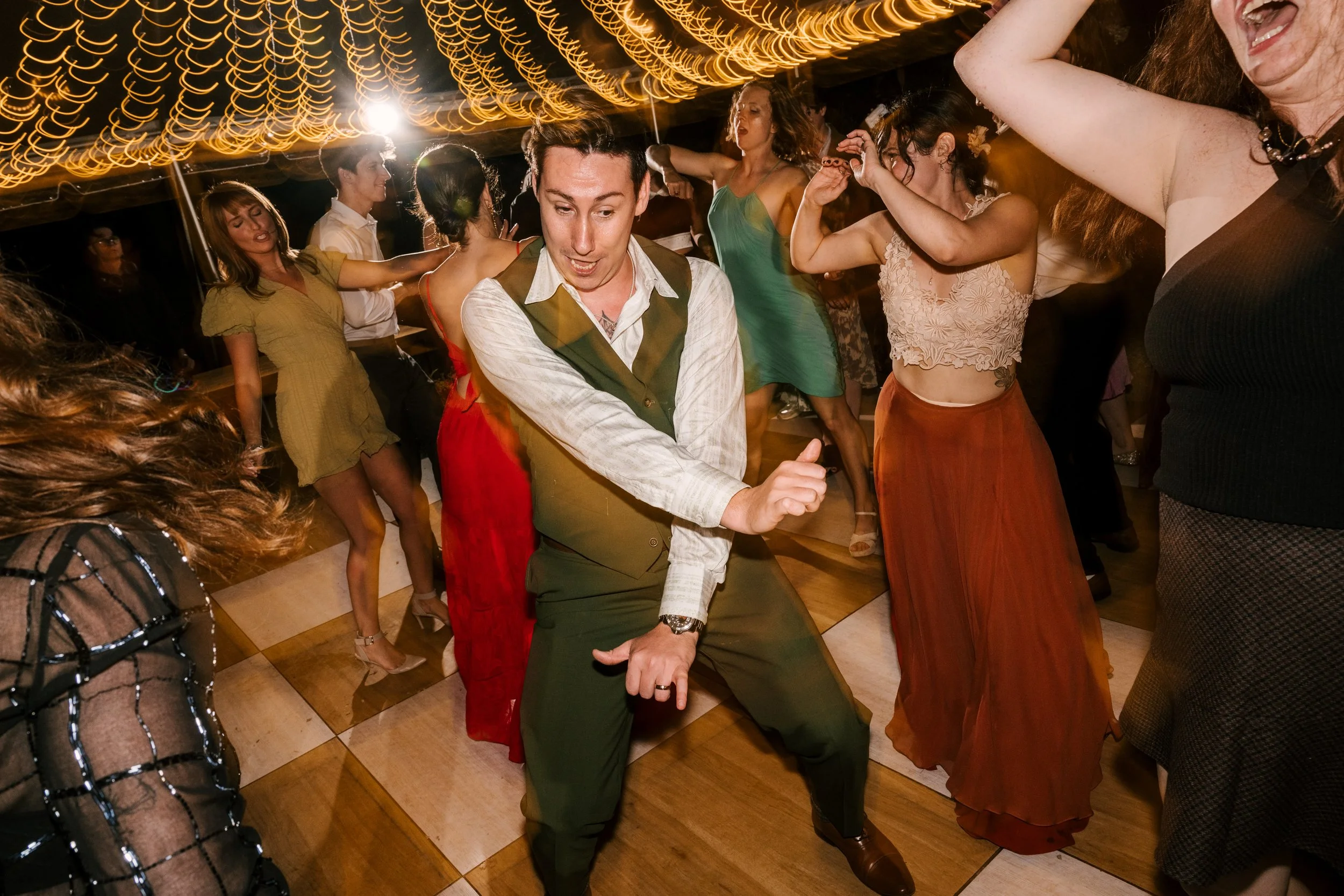 People dancing at an upstate NY wedding with warm lighting and vintage decor.