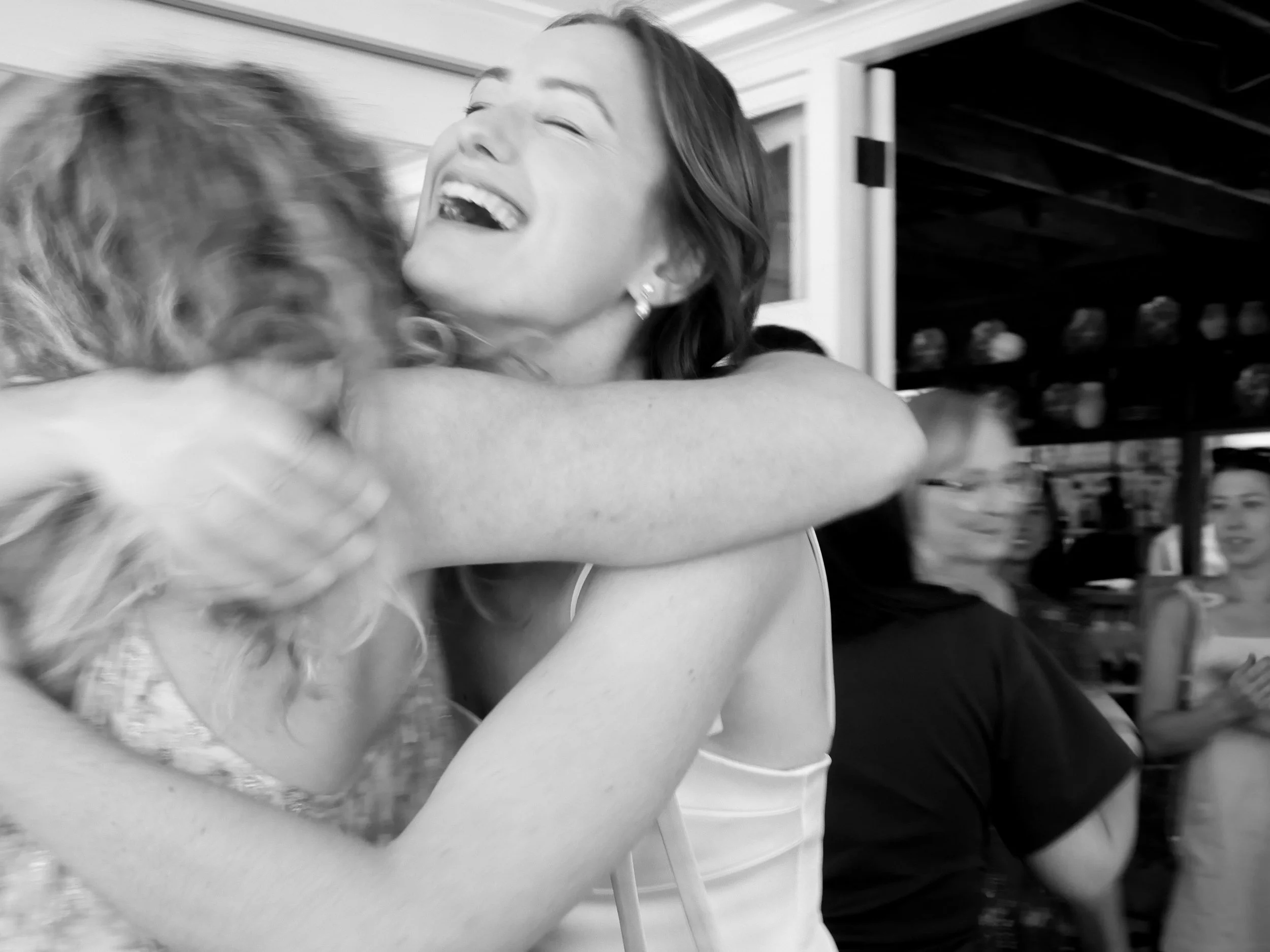 Two women hugging and smiling happily at a hen's party.