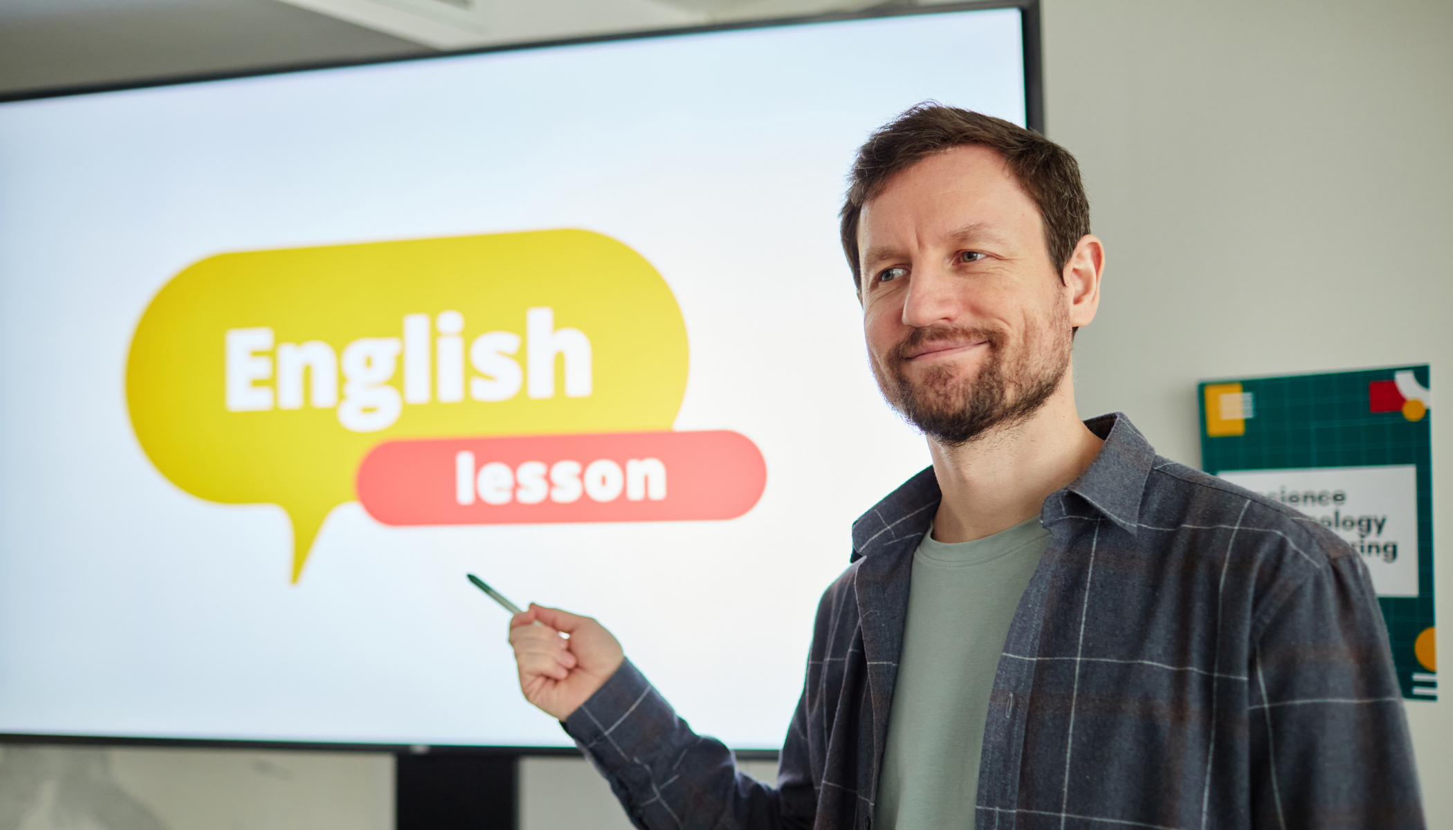 A man standing in front of a screen showing a presentation slide labeled 'English lesson' in a classroom.